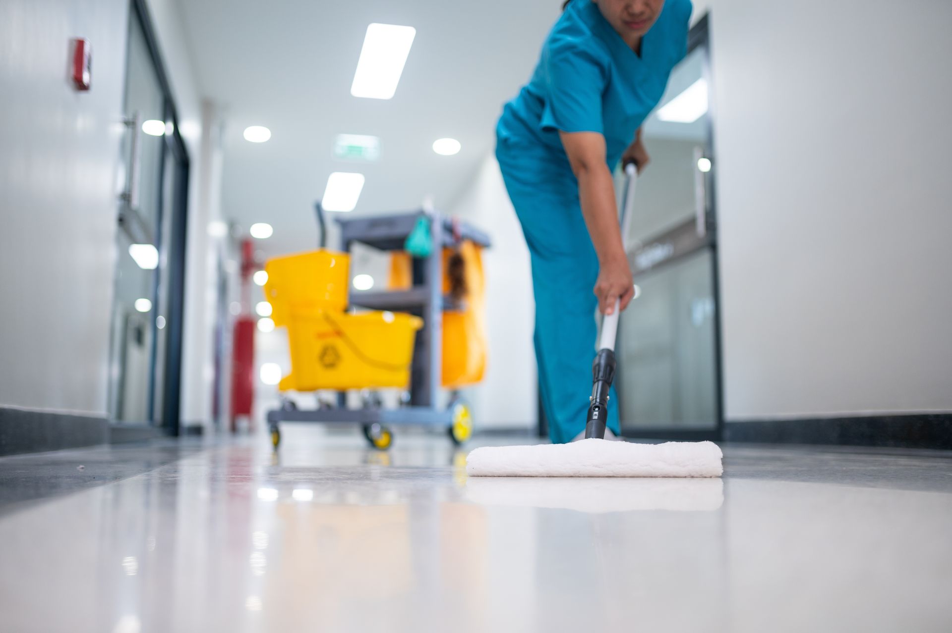 A person in scrubs or a uniform is cleaning an epoxy floor in a medical setting