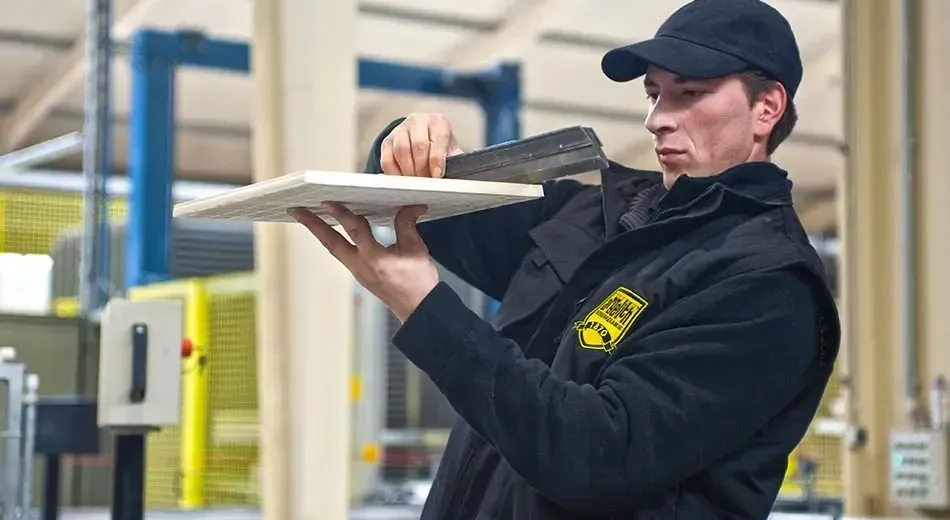 A man is holding a piece of tile checking quality in a factory