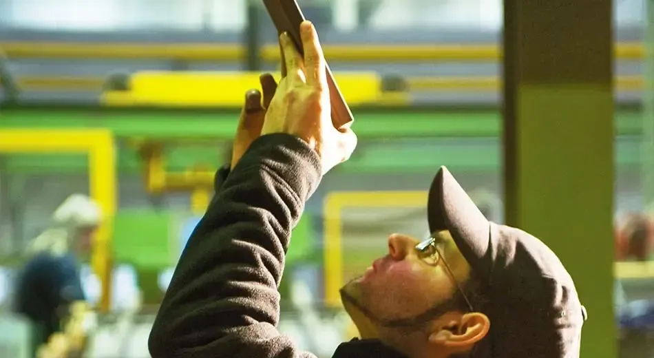 A man in a baseball cap is looking up at the quality of an individual tile