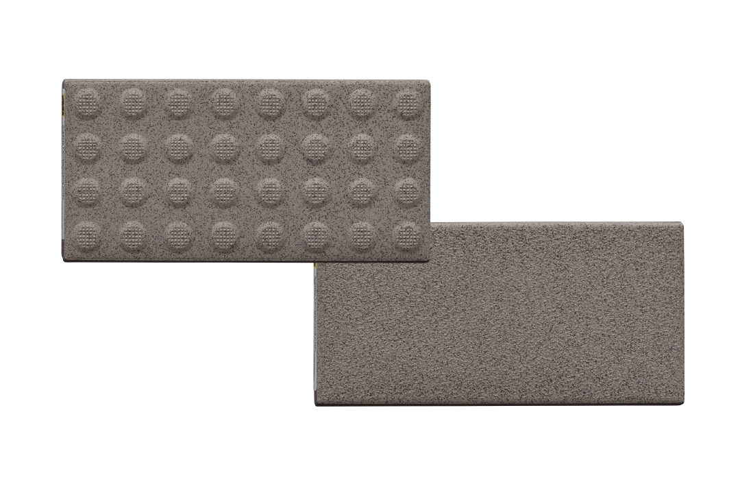 Two gray rectangular tactile paving tiles: one with a raised circular pattern and one smooth surface.vit