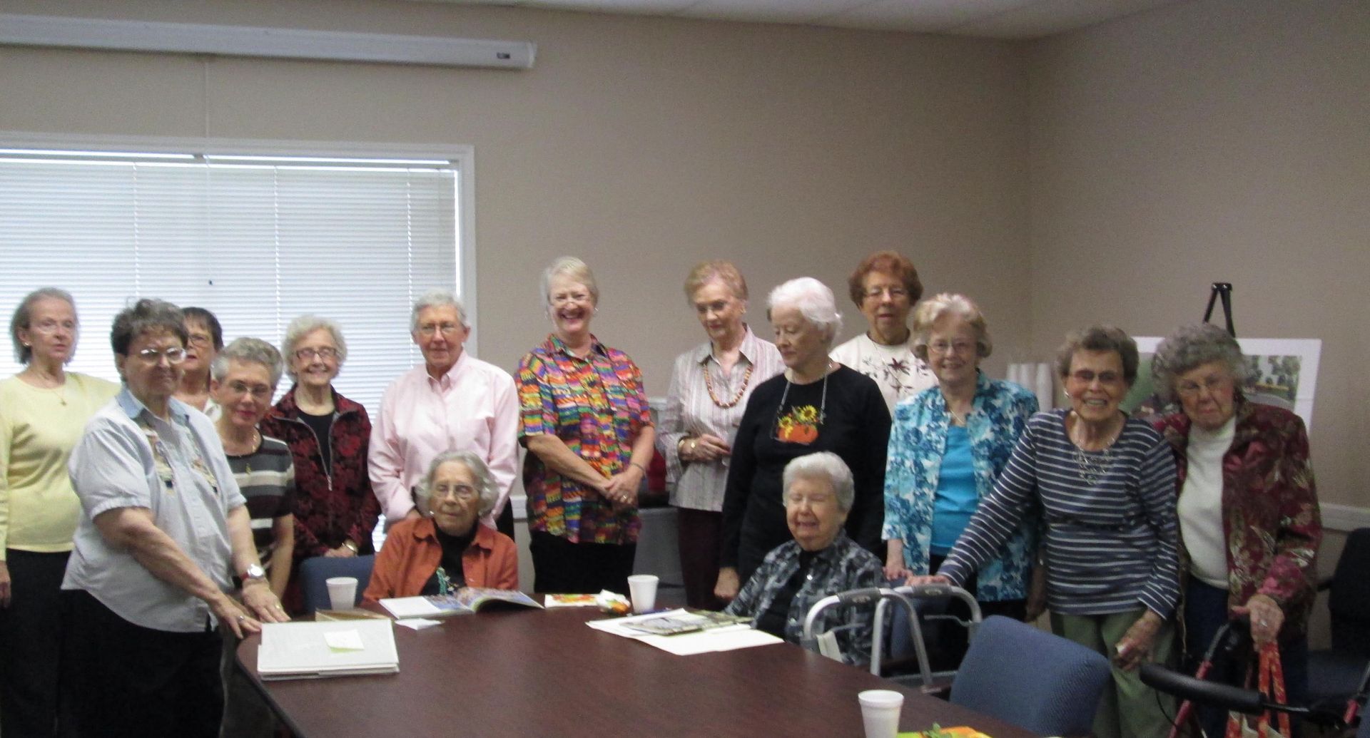 A group of older people are sitting around a table in a room.