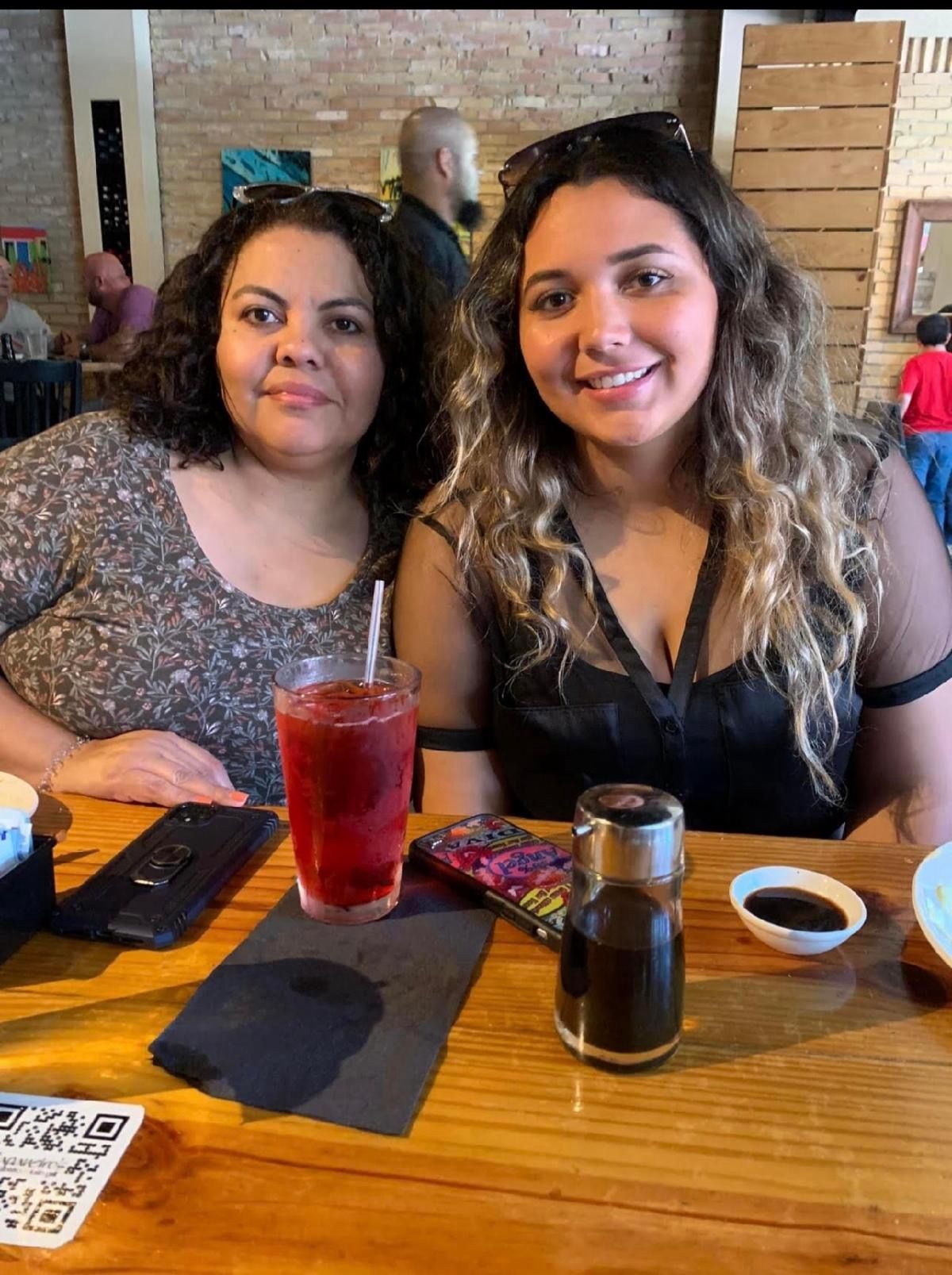Two women are sitting at a table in a restaurant with drinks.