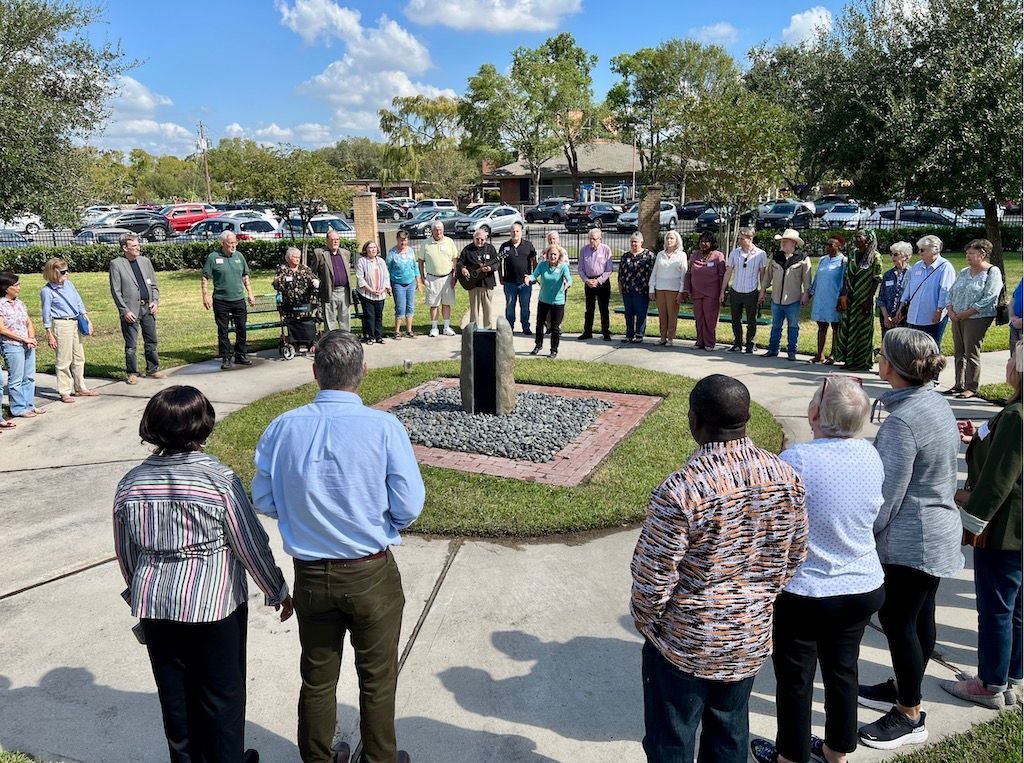A group of people are standing in a circle in front of a fountain.