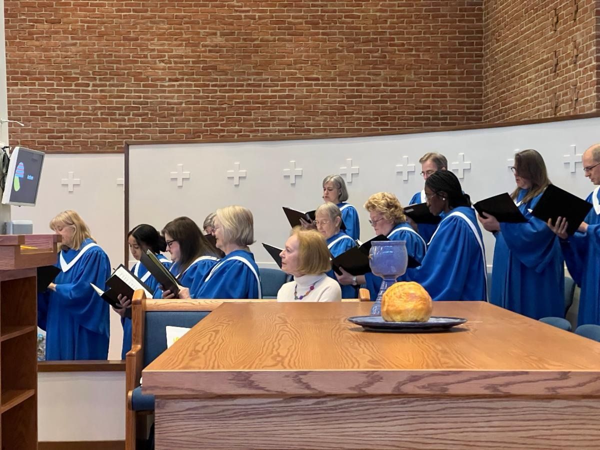 A group of people in blue robes are singing in a church.