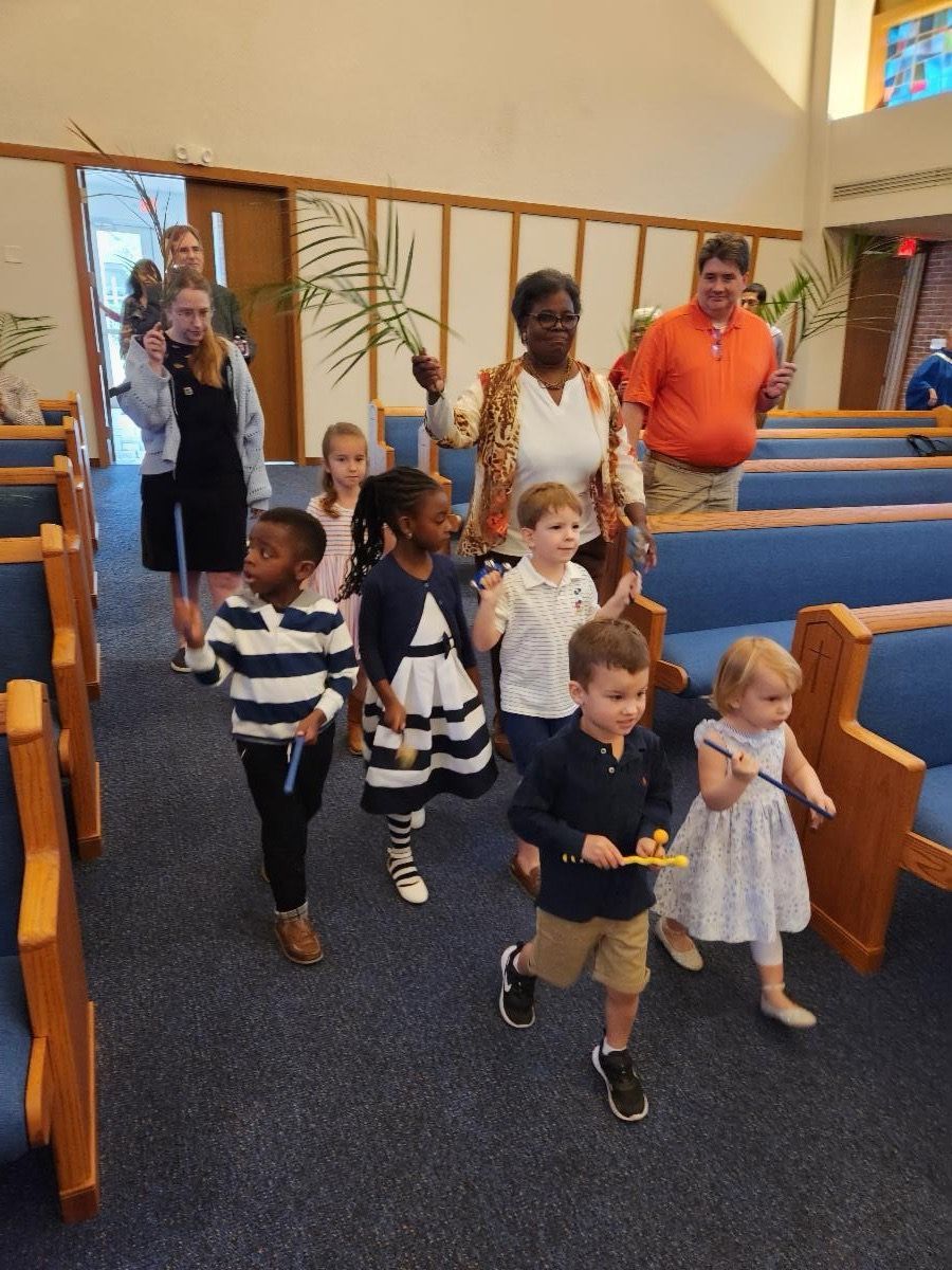 A group of children are walking down a church aisle.