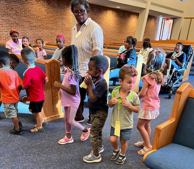 A woman leads a group of children in a church
