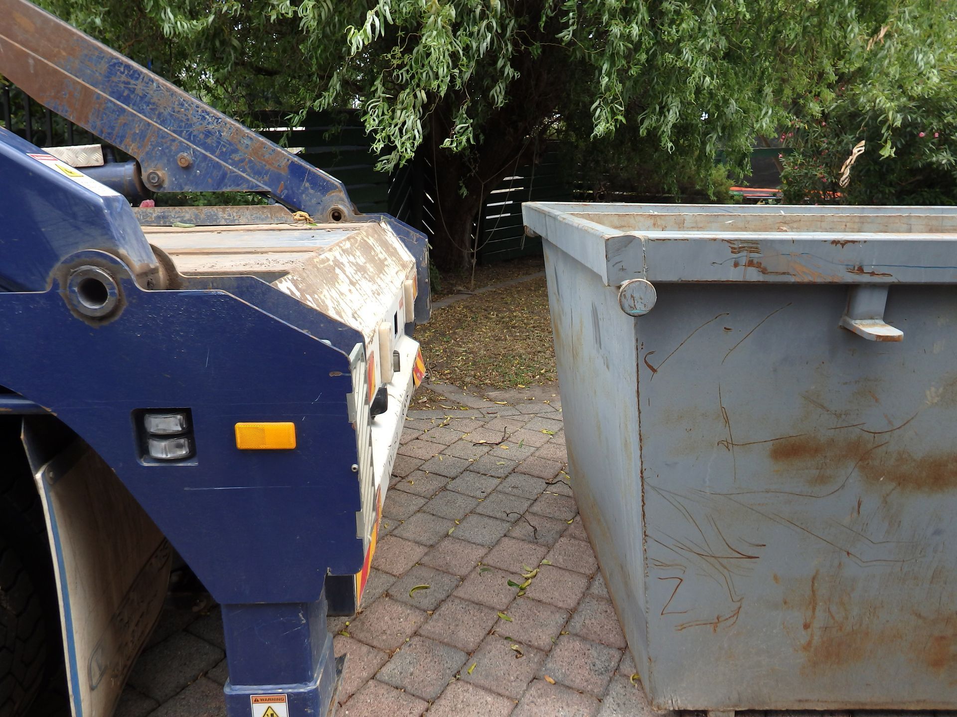A close-up of a grey steel skip bin and truck for pick-up. A close-up of a grey steel skip bin and truck for pick-up.