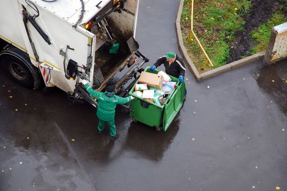 Two workers are loading household rubbish into a garbage truck in a residential area Two workers are loading household rubbish into a garbage truck in a residential area