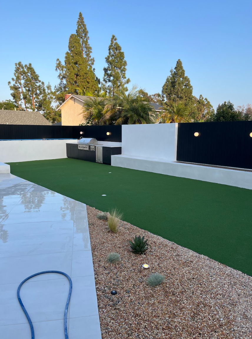 Modern backyard patio with pool, artificial turf, gravel, and a black-and-white privacy wall