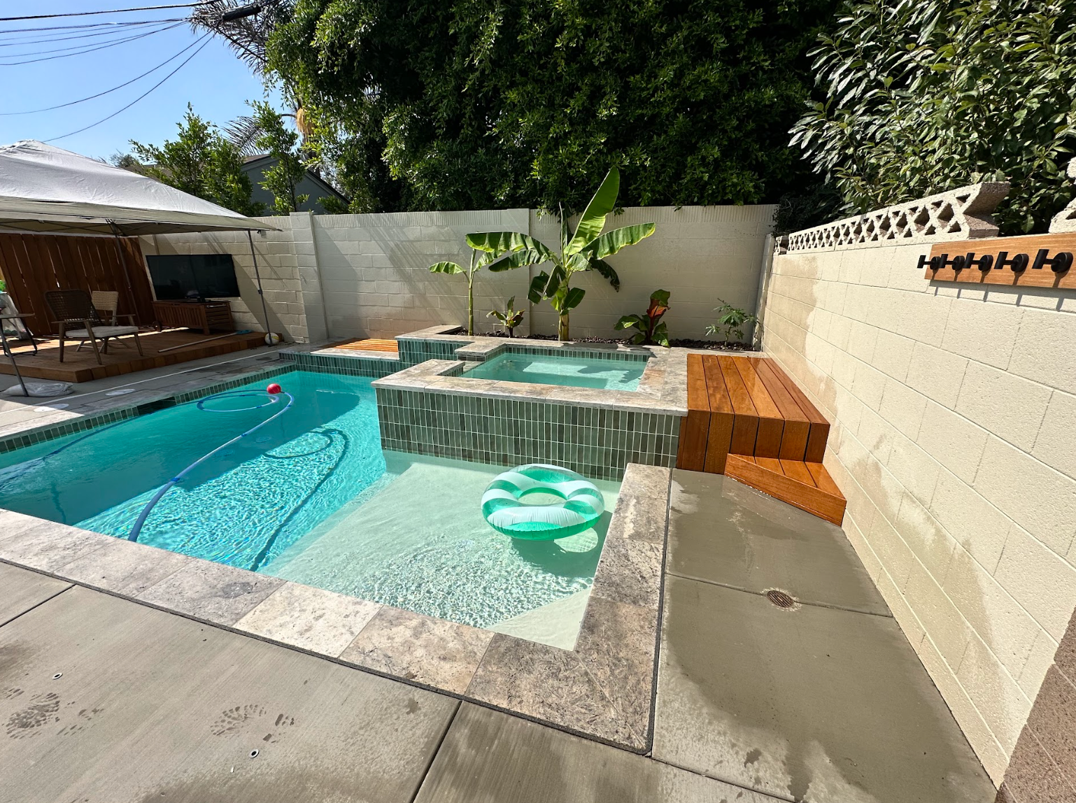 Backyard pool and hot tub with turquoise water, patio seating, and a small float near the steps