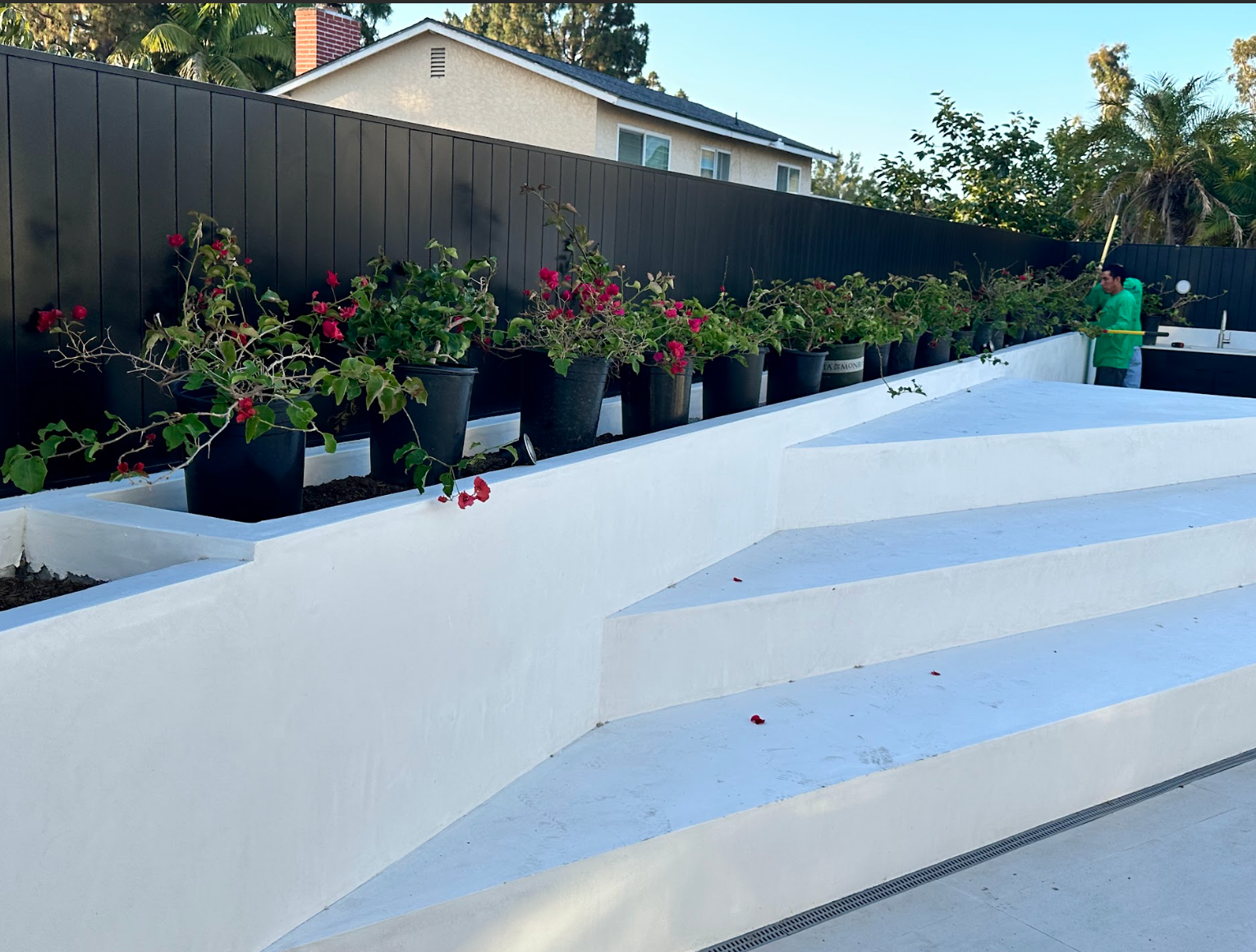 White stepped patio with black fence and hanging flower pots along the left side