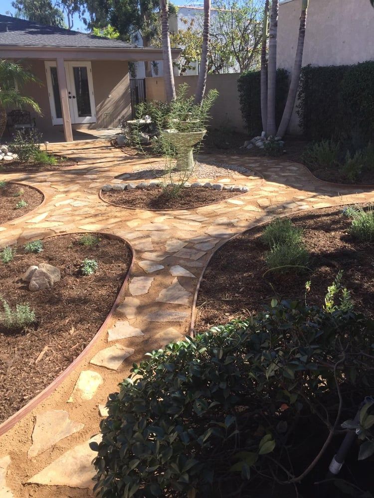 Curved stone garden path through landscaped yard leading to a house entrance
