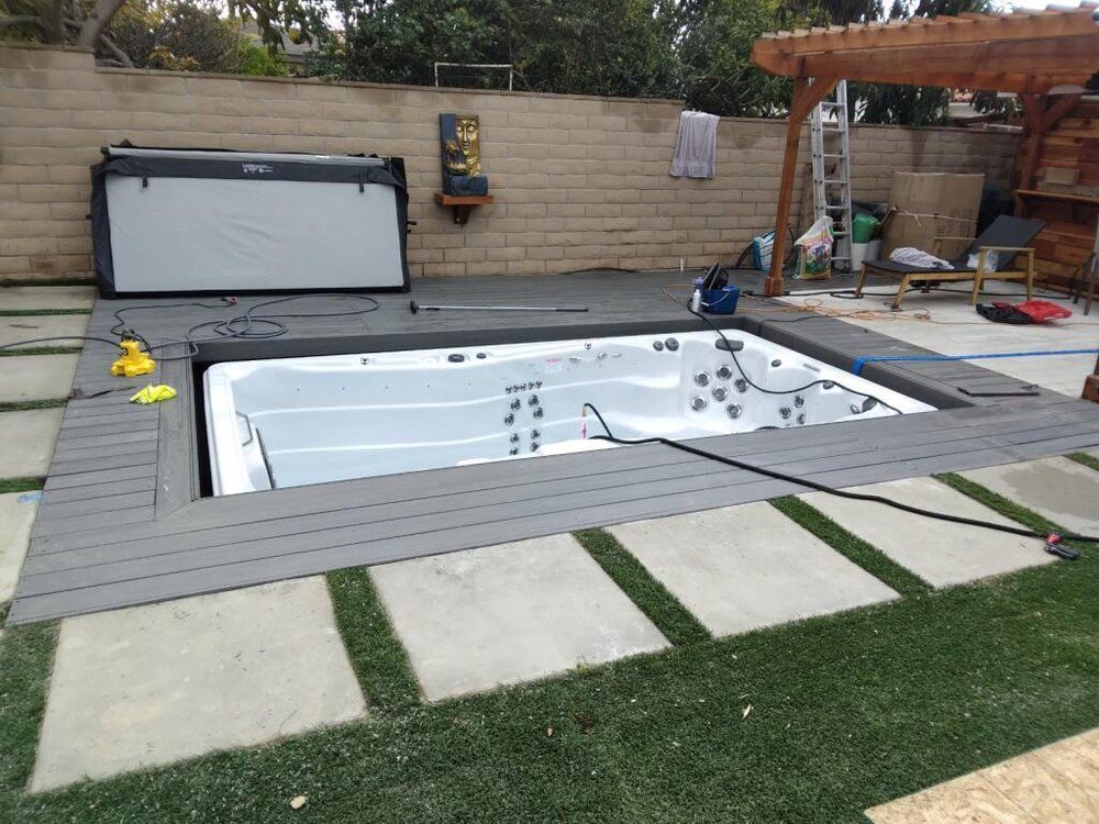Backyard with a covered in-ground hot tub, stone pavers, and a wooden pergola.