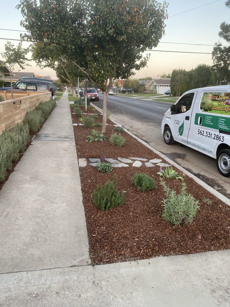 Sidewalk beside a landscaped street with a tree and parked white van at dusk