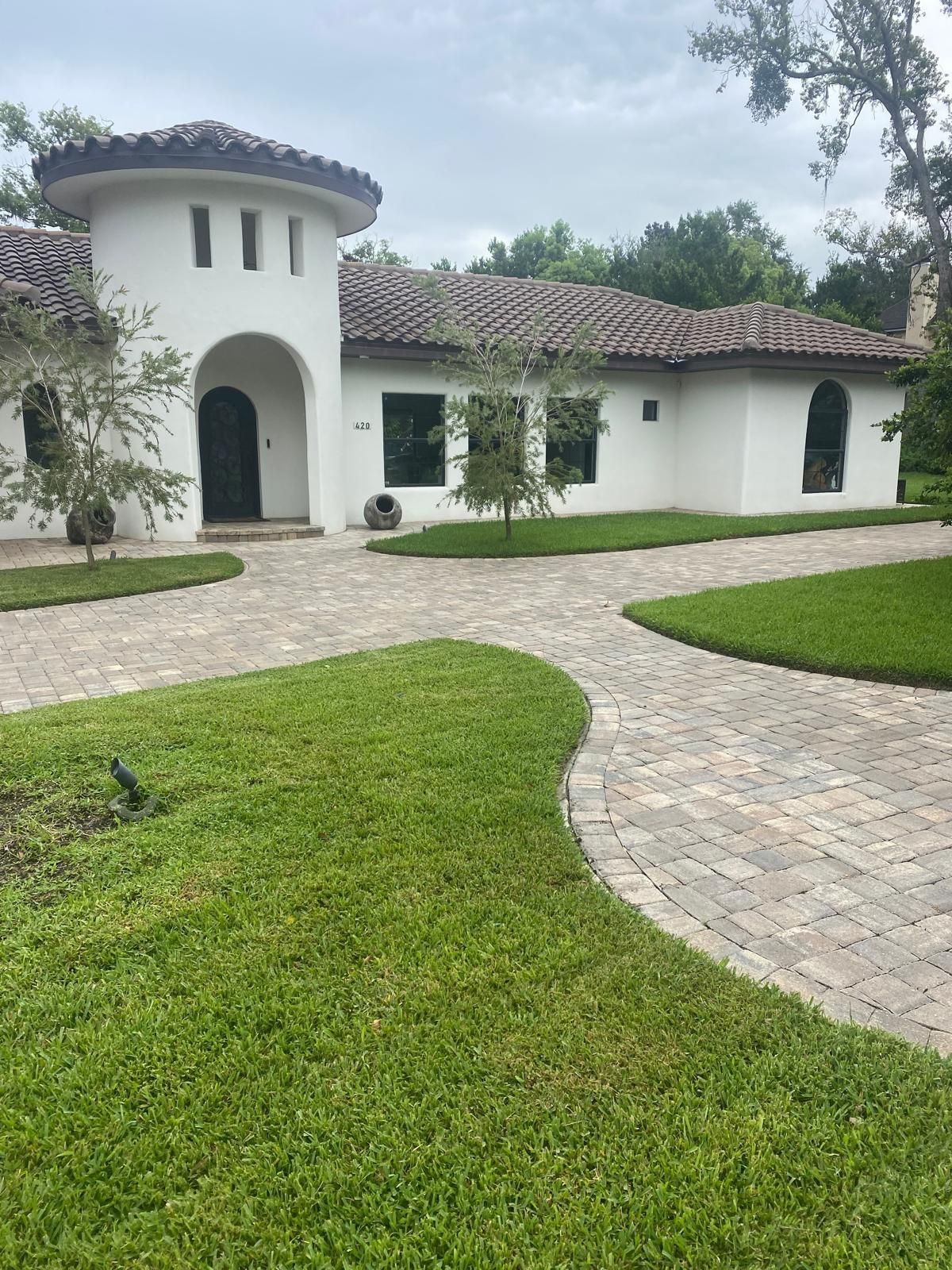 A white house with a brick driveway leading to it