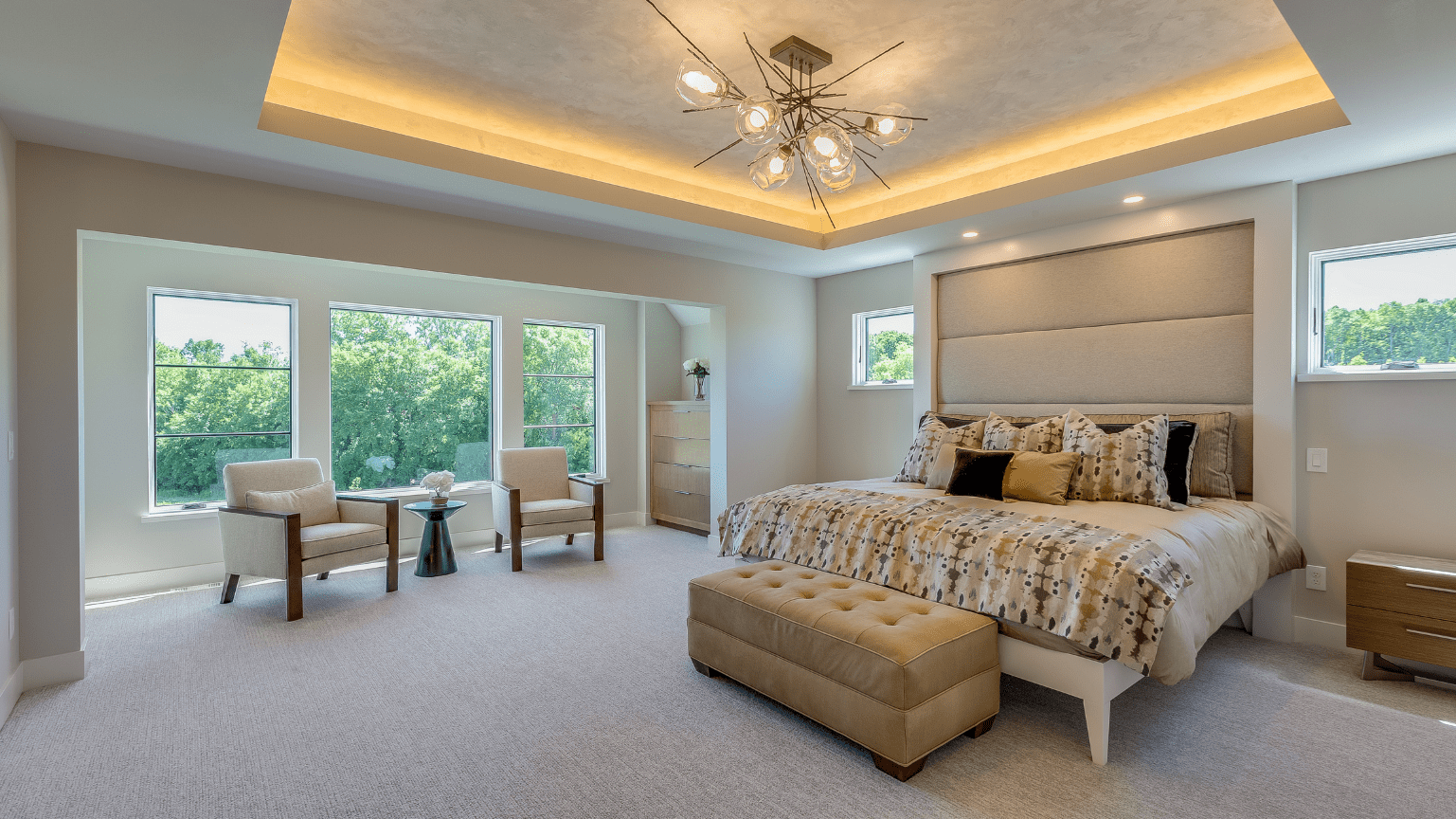 Spacious bedroom with large windows, king bed, seating area, neutral colors, and decorative ceiling lights — Intolec Electrical In Tweed Heads, NSW