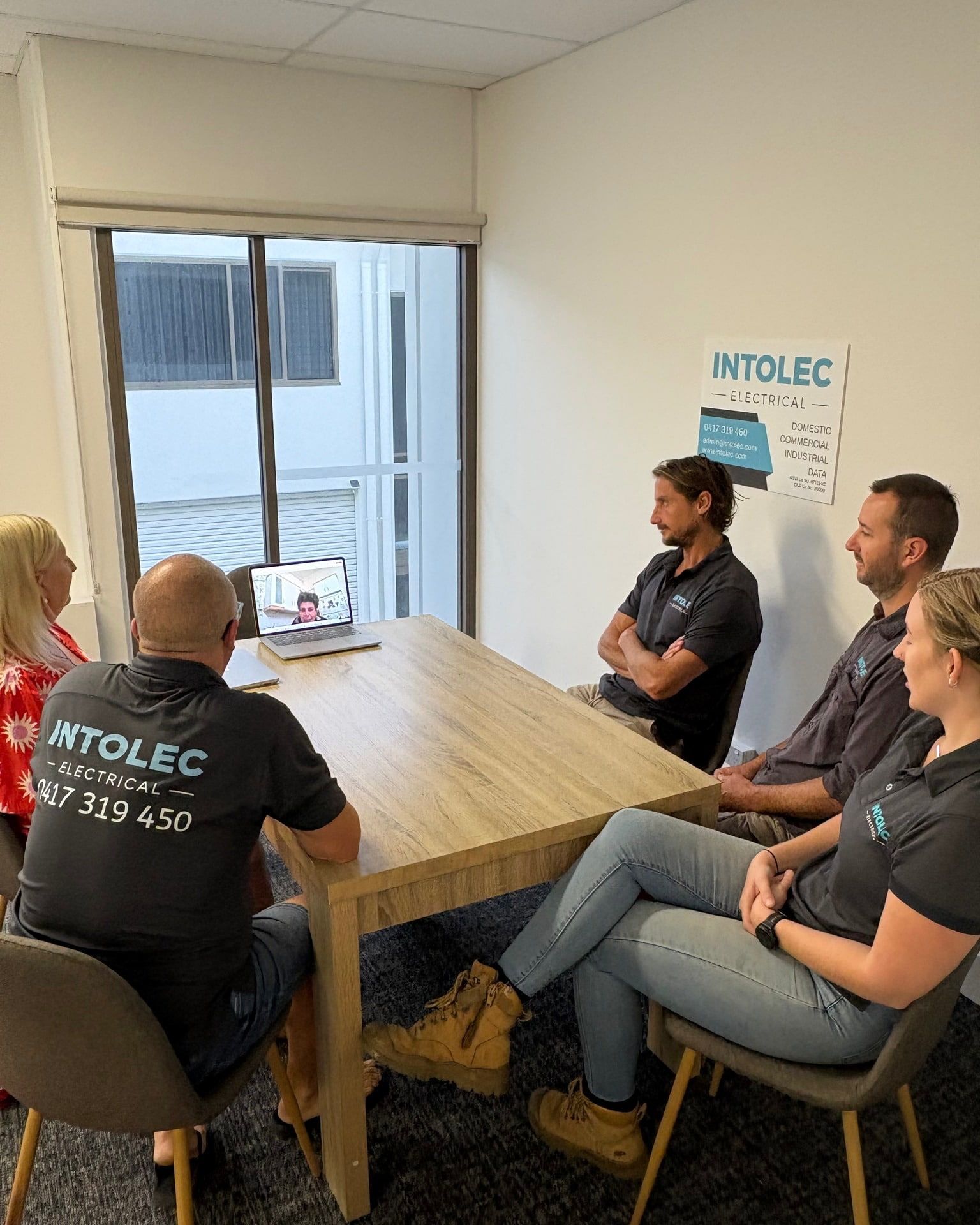 Five People at a Table; Some Wearing Intolec Shirts — Intolec Electrical In Tweed Heads, NSW