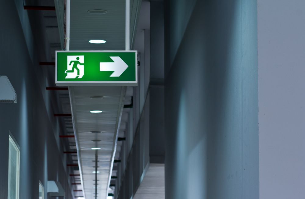Hallway With Exit Door, Fire Equipment, and Stairs. Green Exit Sign Above Doorway — Intolec Electrical In Lismore, NSW