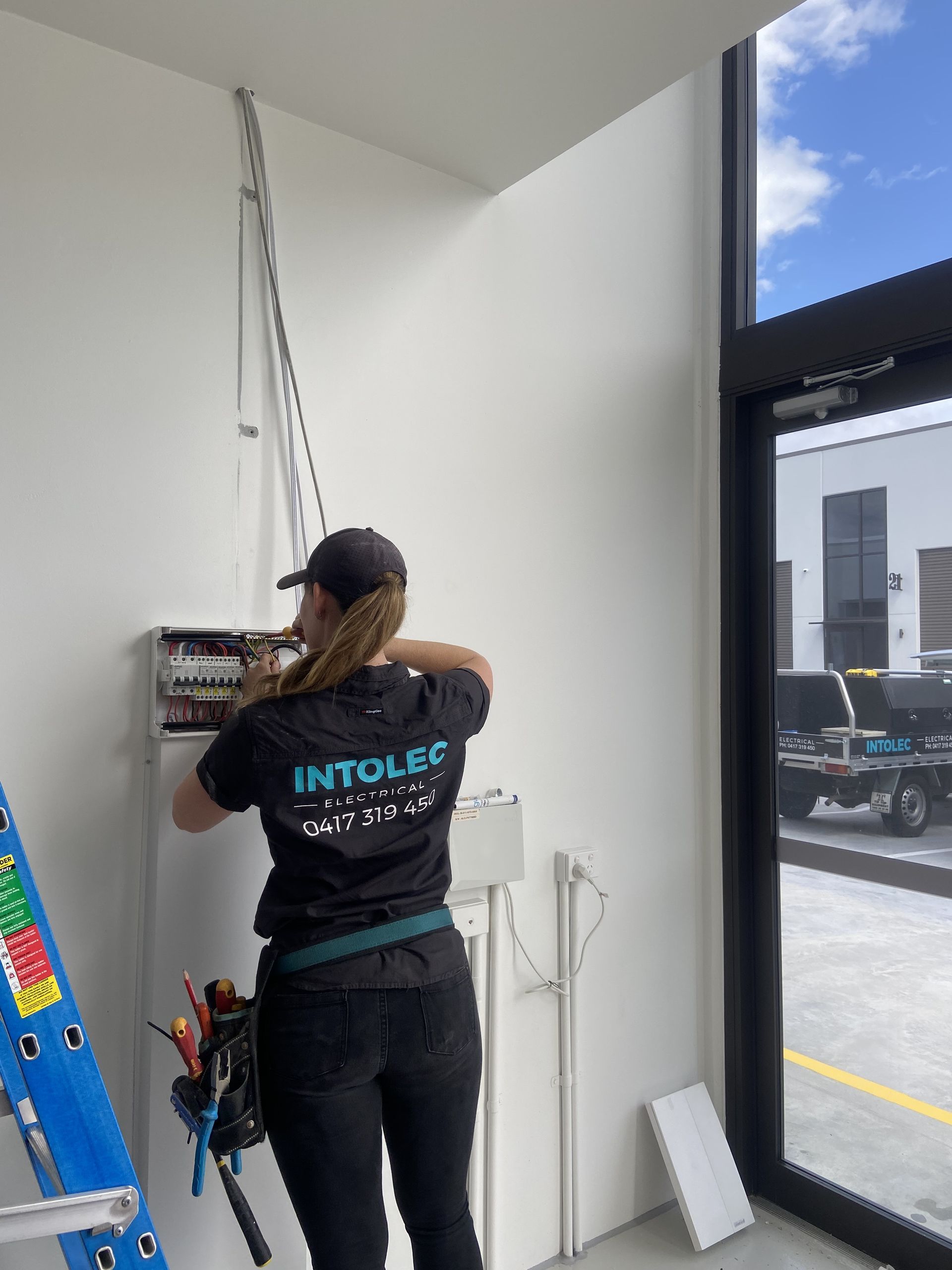 Woman Electrician Works on Electrical Panel Indoors — Intolec Electrical in Tweed Heads, NSW