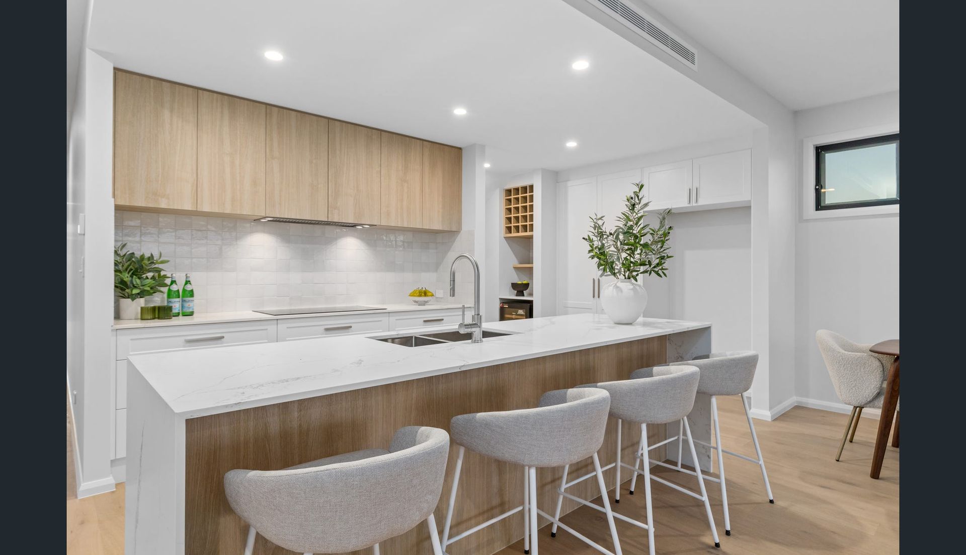 Modern Kitchen With Light Wood Cabinets, White Countertops, and Bar Stools — Intolec Electrical in Tweed Heads, NSW
