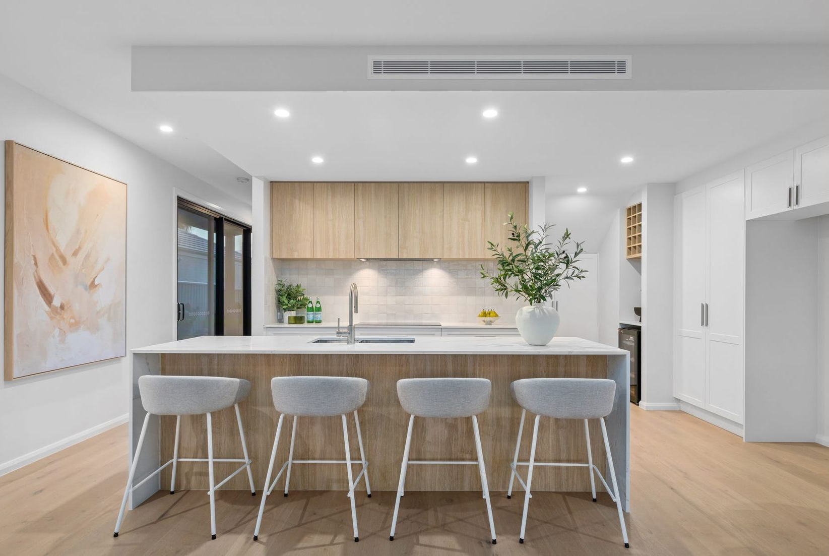 White kitchen with pendant lights, stainless steel appliances, and a marble countertop. — Intolec Electrical In Tweed Heads, NSW