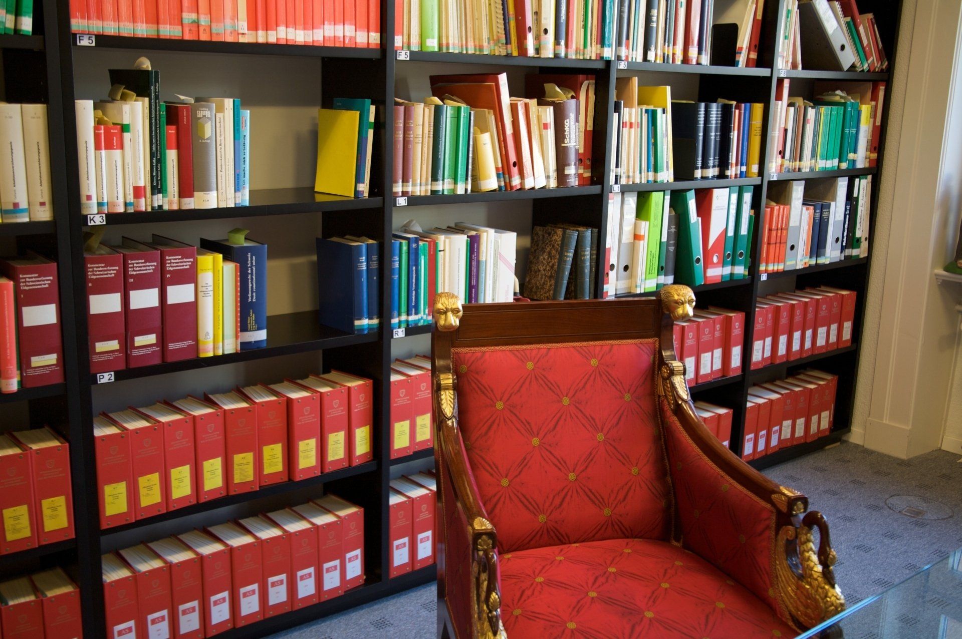A red chair sits in front of a bookshelf full of law books