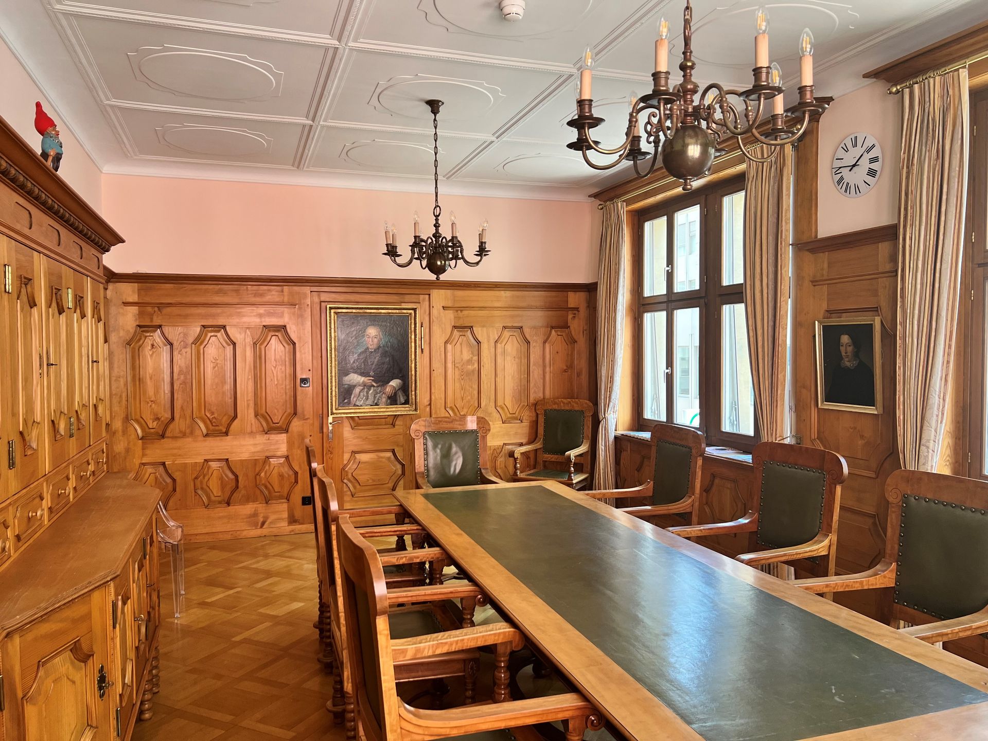A room with a long table and chairs and a clock on the wall