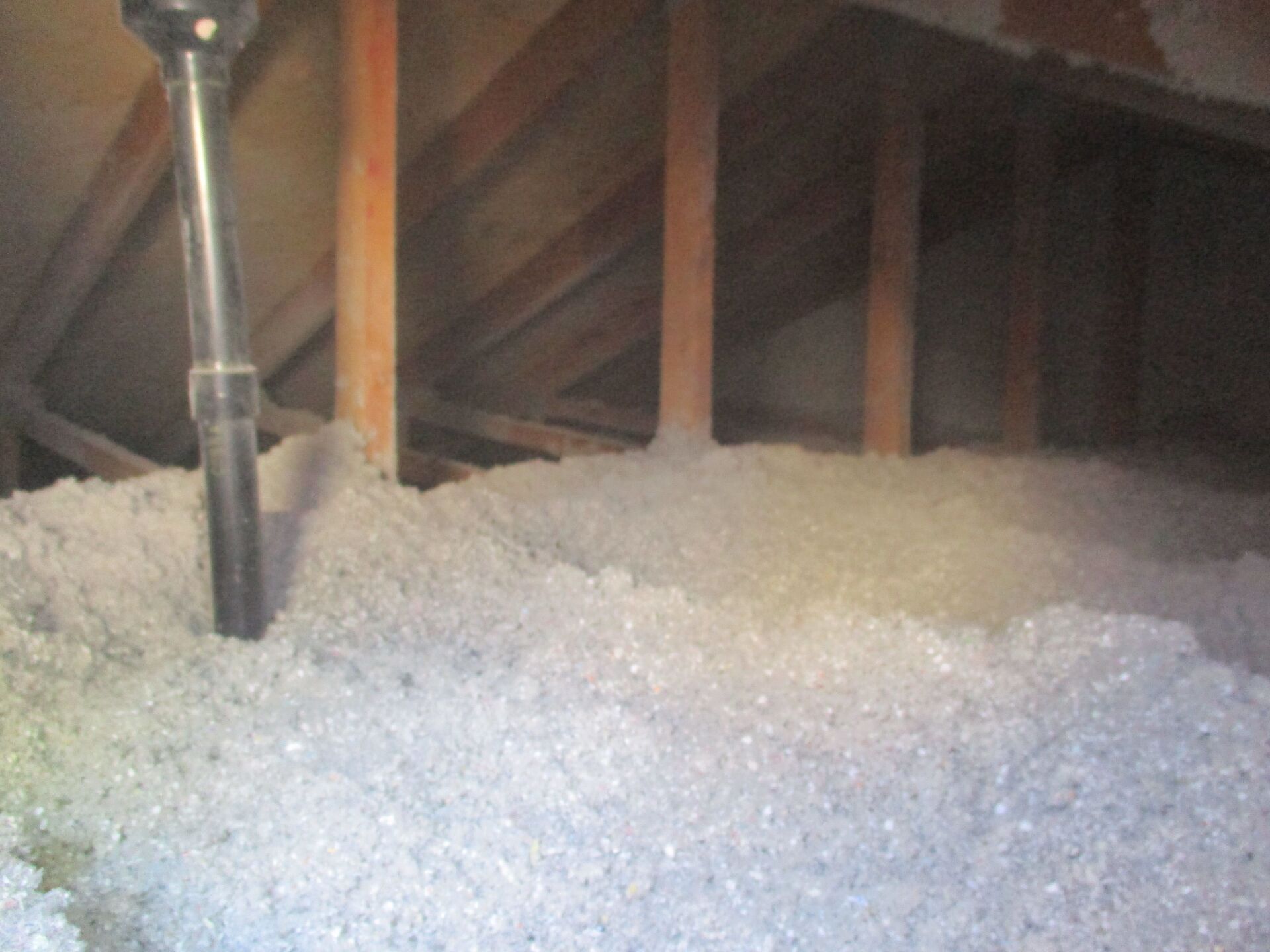 A pile of styrofoam is being blown into an attic.