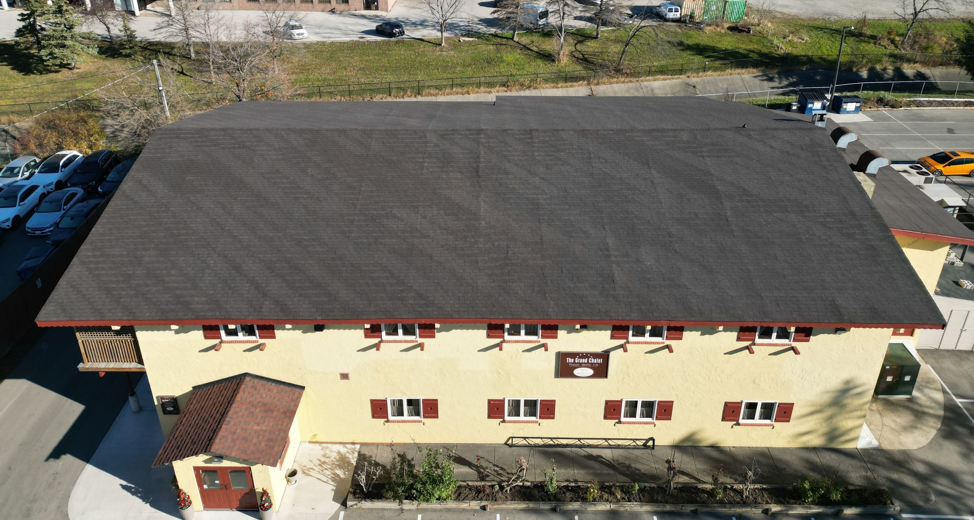 Aerial view of a beige building with a dark roof in an industrial area.