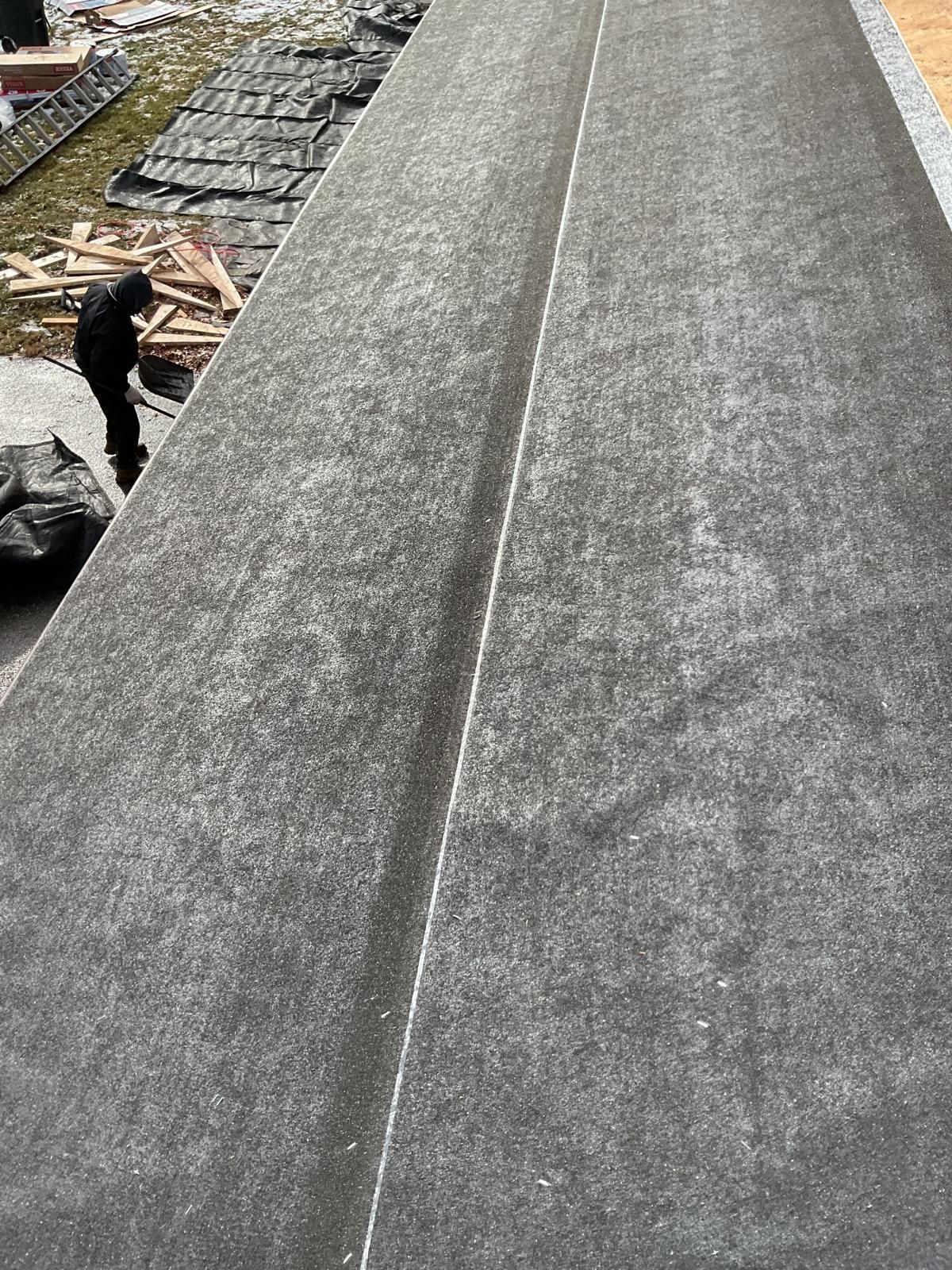 A person in black clothing stands next to a gray, textured surface on a construction site.