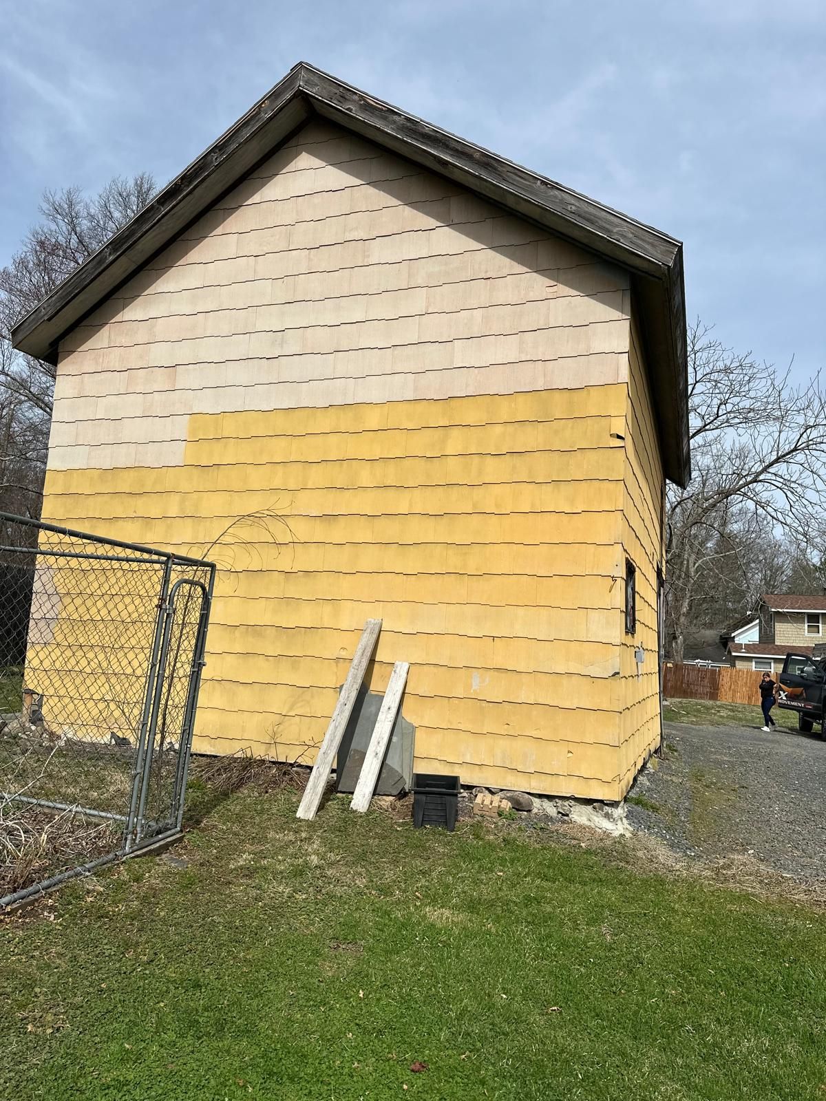 A side view of a house exterior with unfinished siding, showing yellow foam boards on the lower half and light panels above.