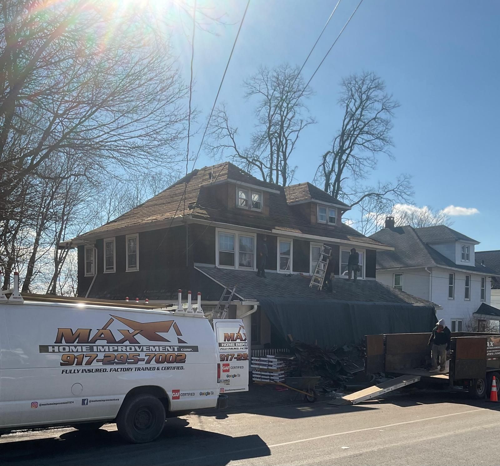 Roofing contractors work on a house while a white 