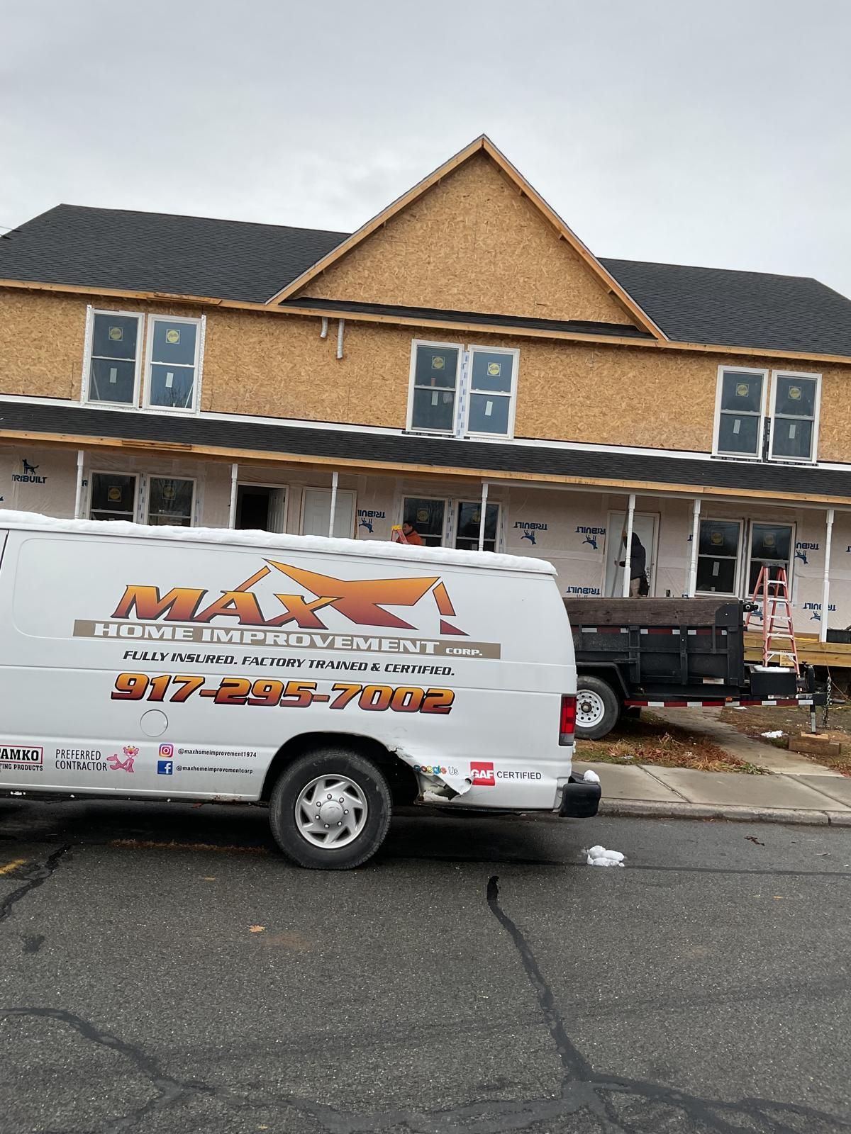 A Max Home Improvement van parked in front of a two-story residential building under construction.