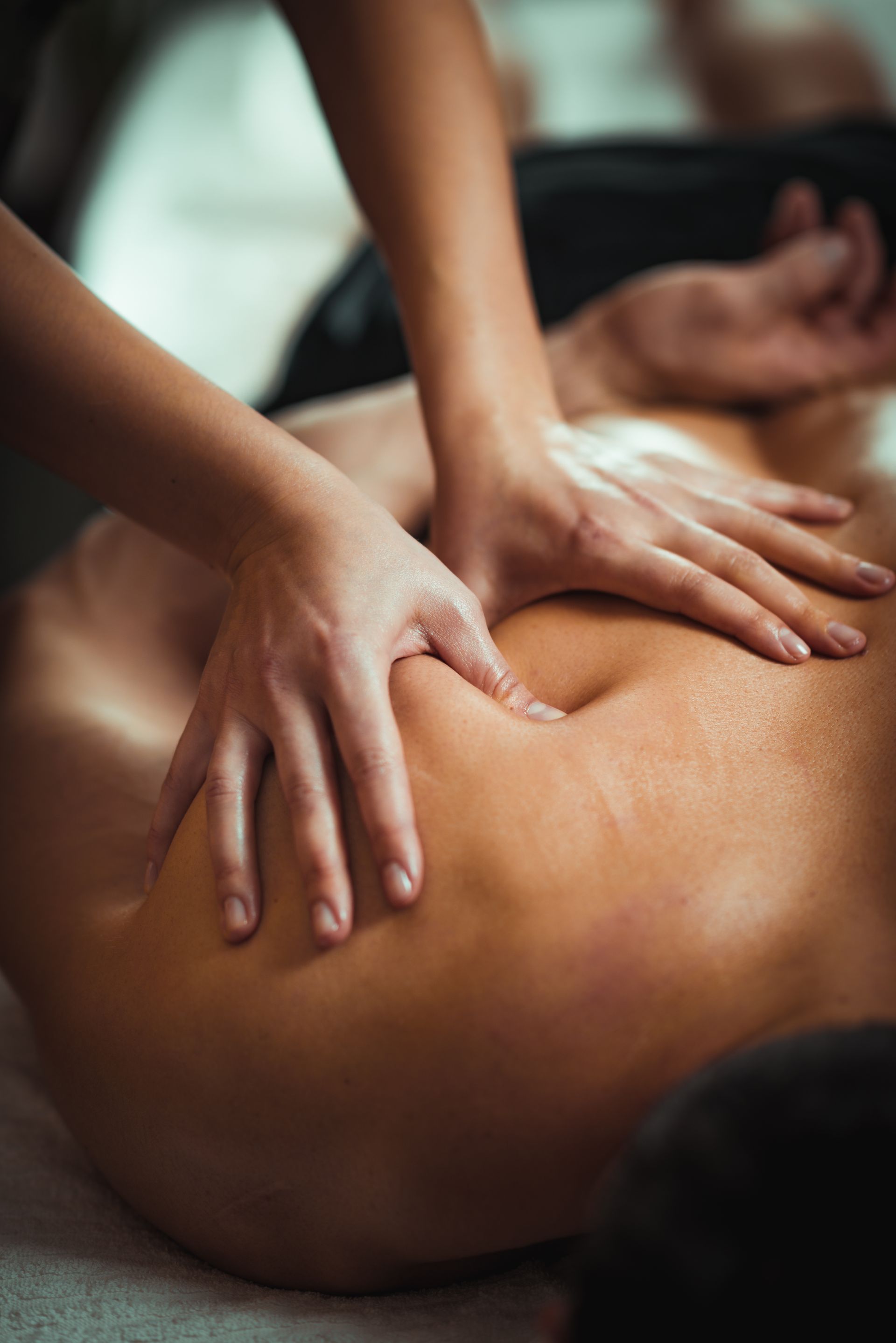 Hands giving a back massage, applying pressure to the shoulder area.