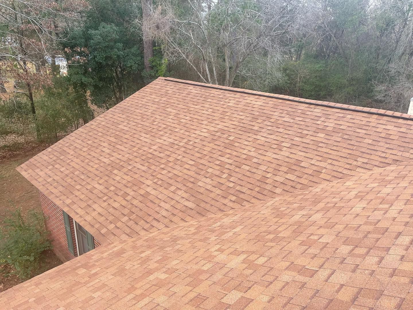 An aerial view of a roof of a house with trees in the background.