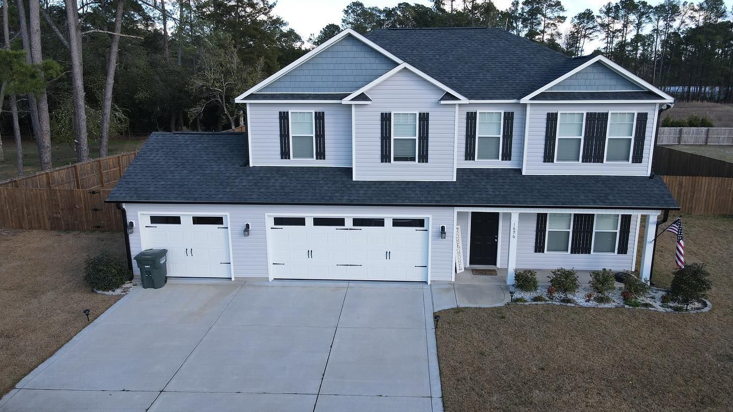 An aerial view of a large white house with a black roof