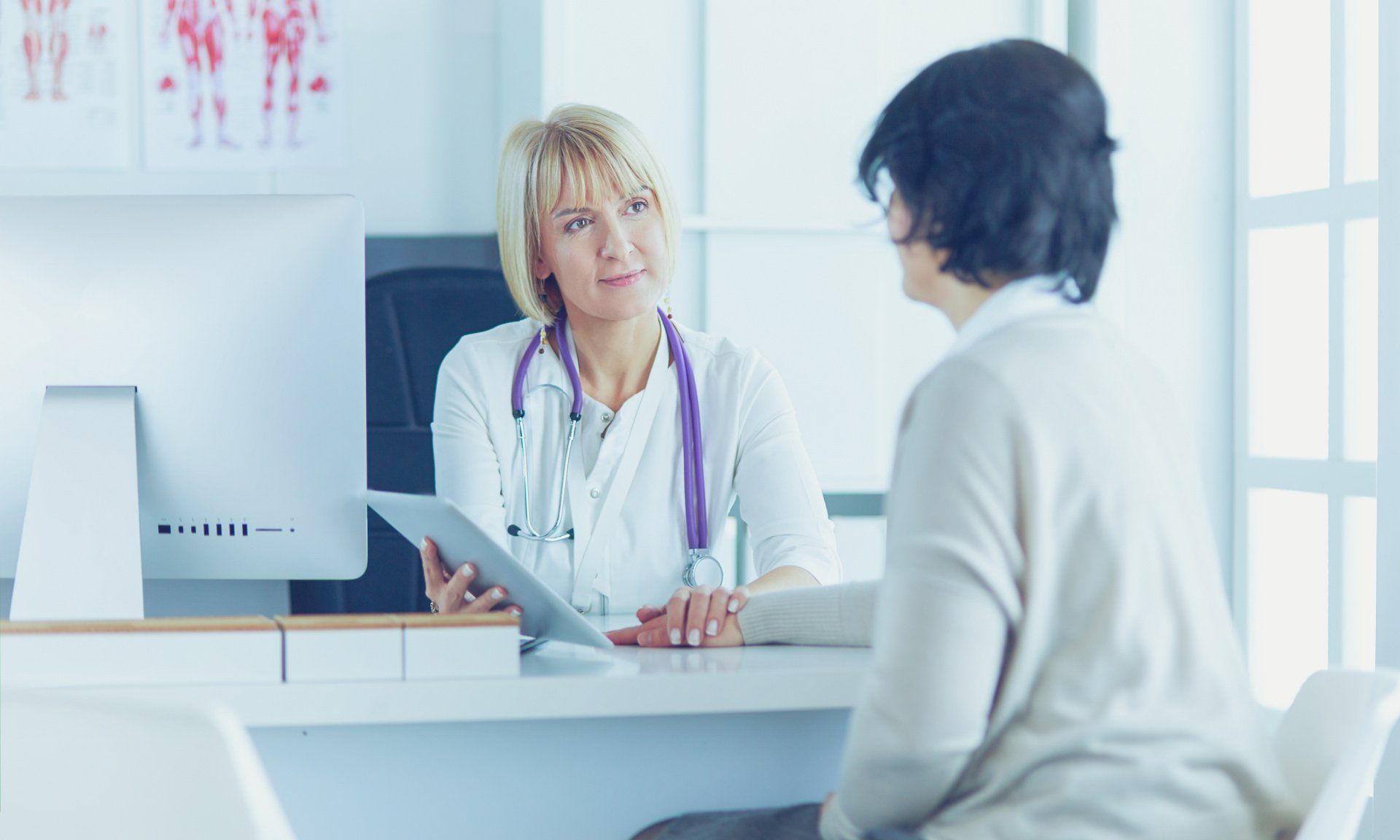 A doctor is talking to a patient who is sitting at a desk.