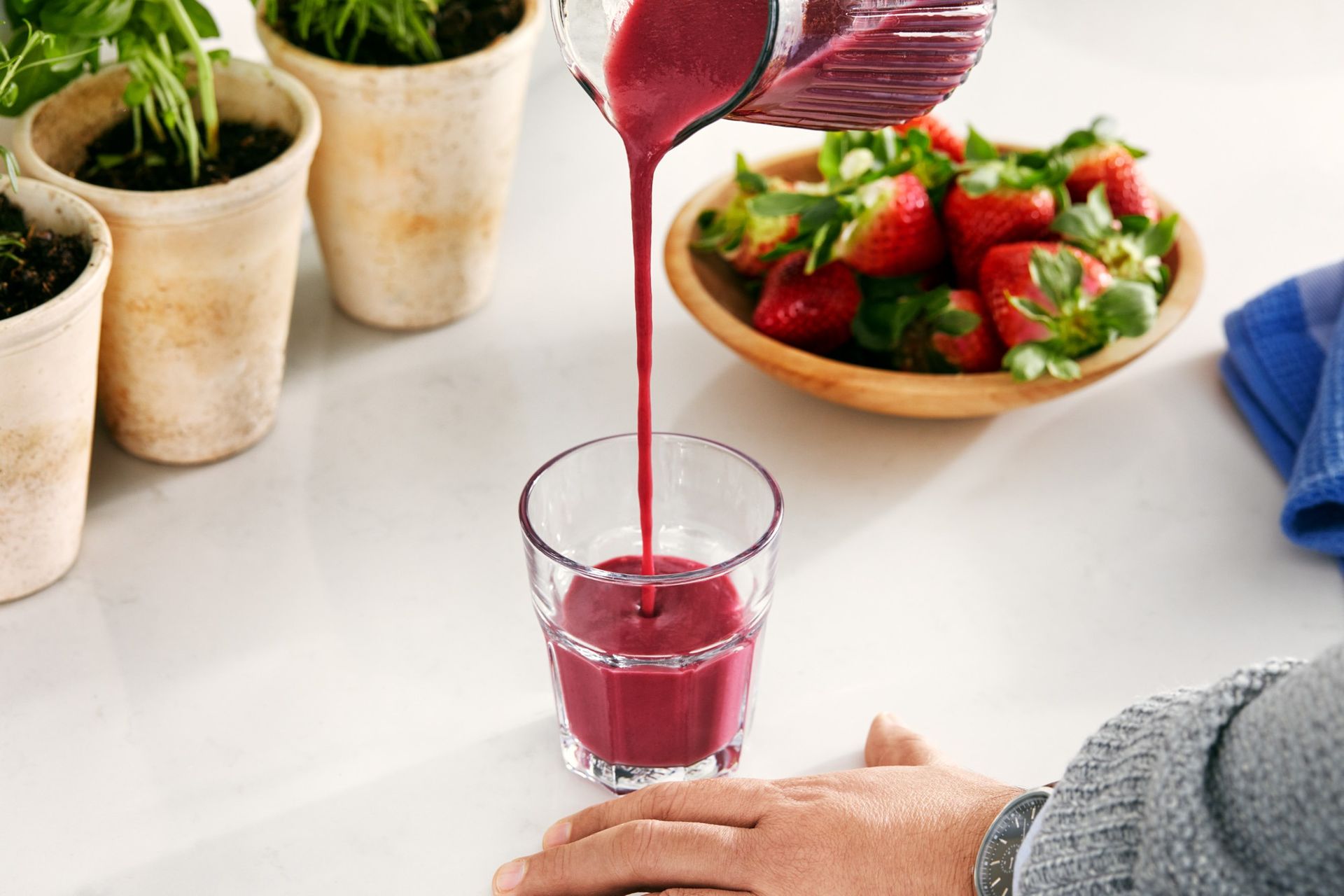 A person is pouring a smoothie into a glass.
