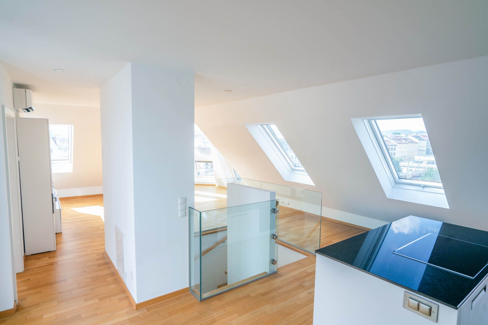 Helles, modernes Interieur mit Oberlichtern und Glasgeländer. Helle Holzböden, weiße Wände.