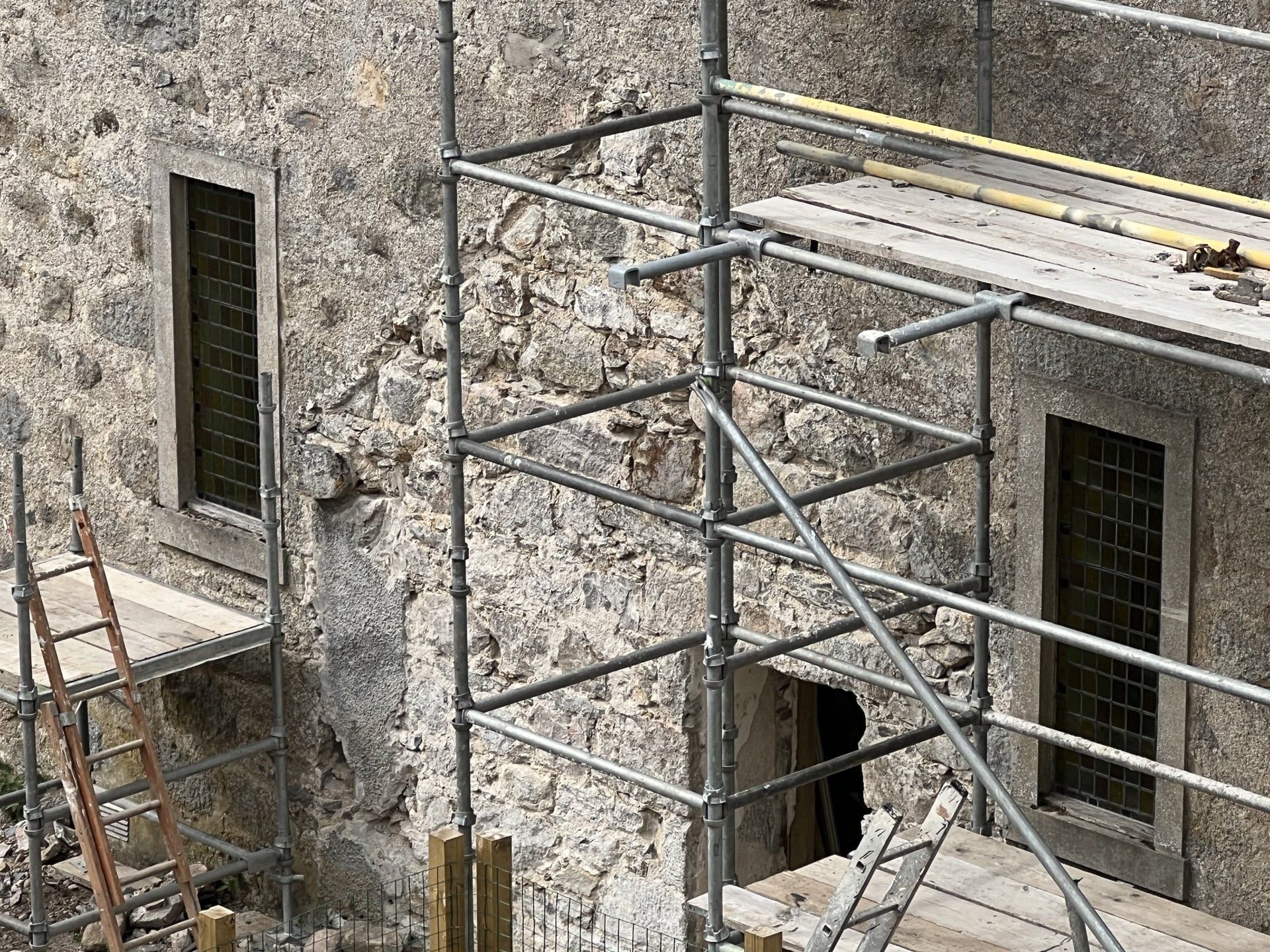Stone building wall with scaffolding and open windows during renovation