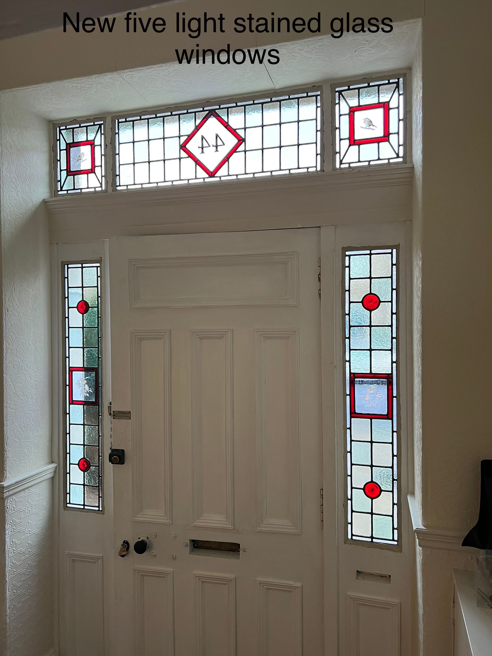 Front door with five new stained-glass windows, featuring red and clear geometric accents.