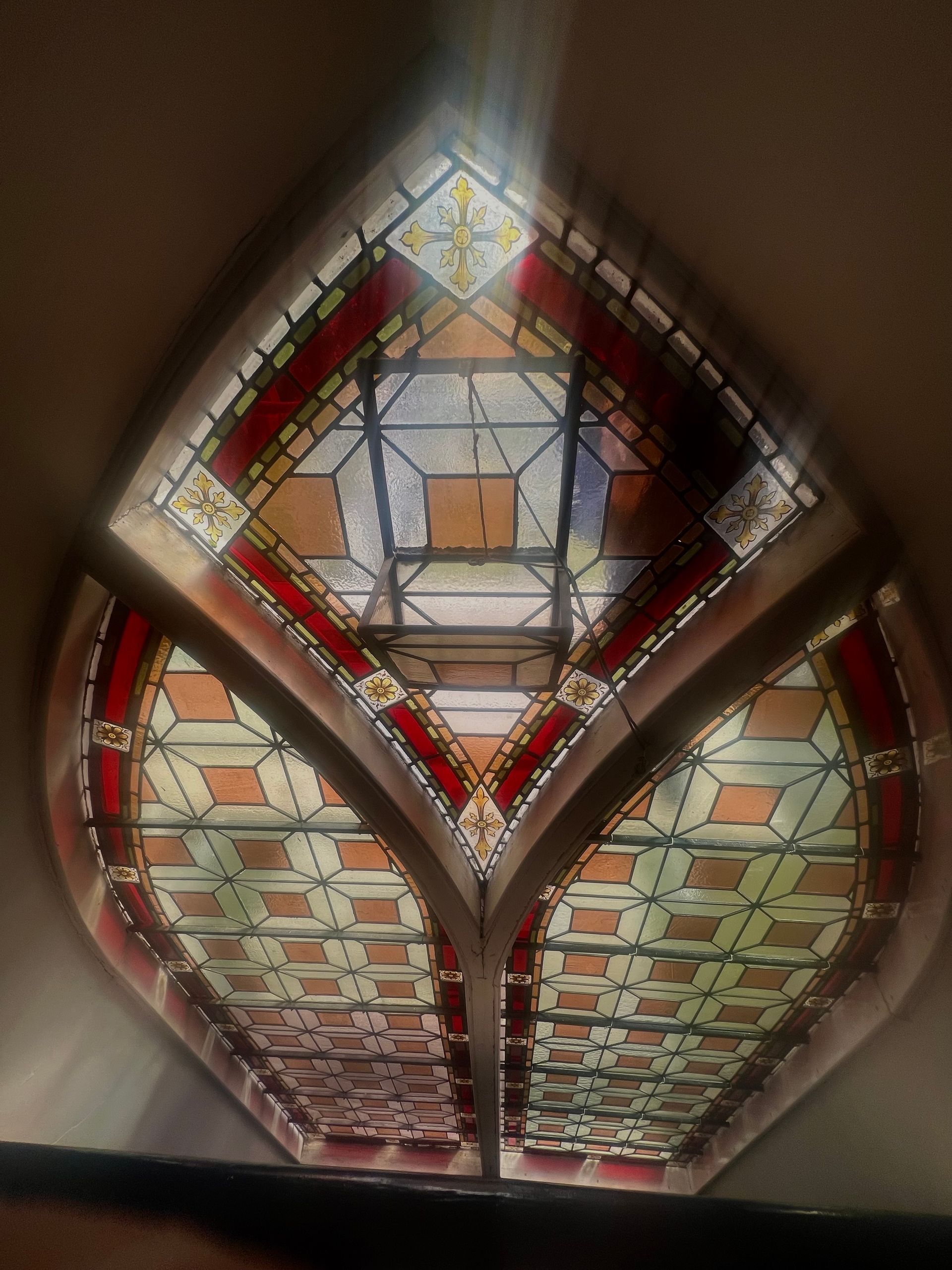 Stained glass window with red, green, and clear geometric panes in a diamond shape