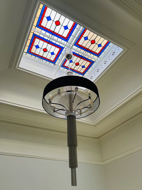 Decorative ceiling fixture with stained-glass panels and a hanging black pendant light in a room corner