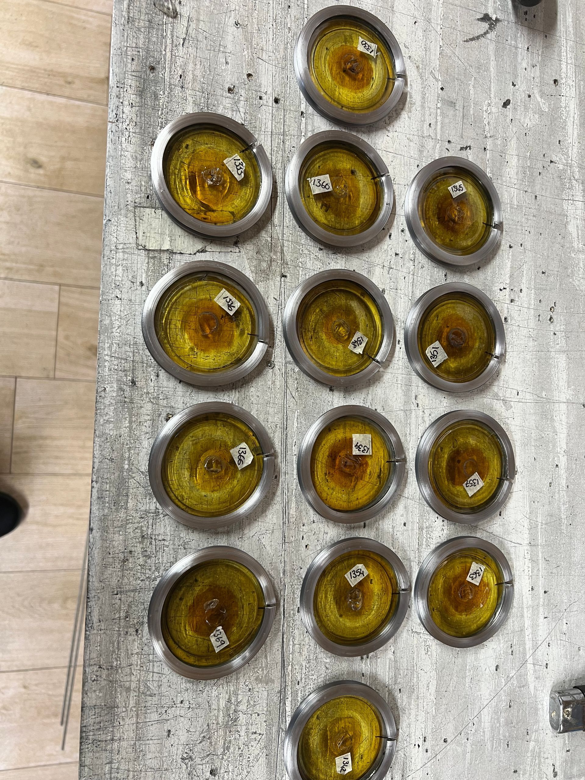 Five small amber glass cups arranged in rows on a weathered wooden surface.
