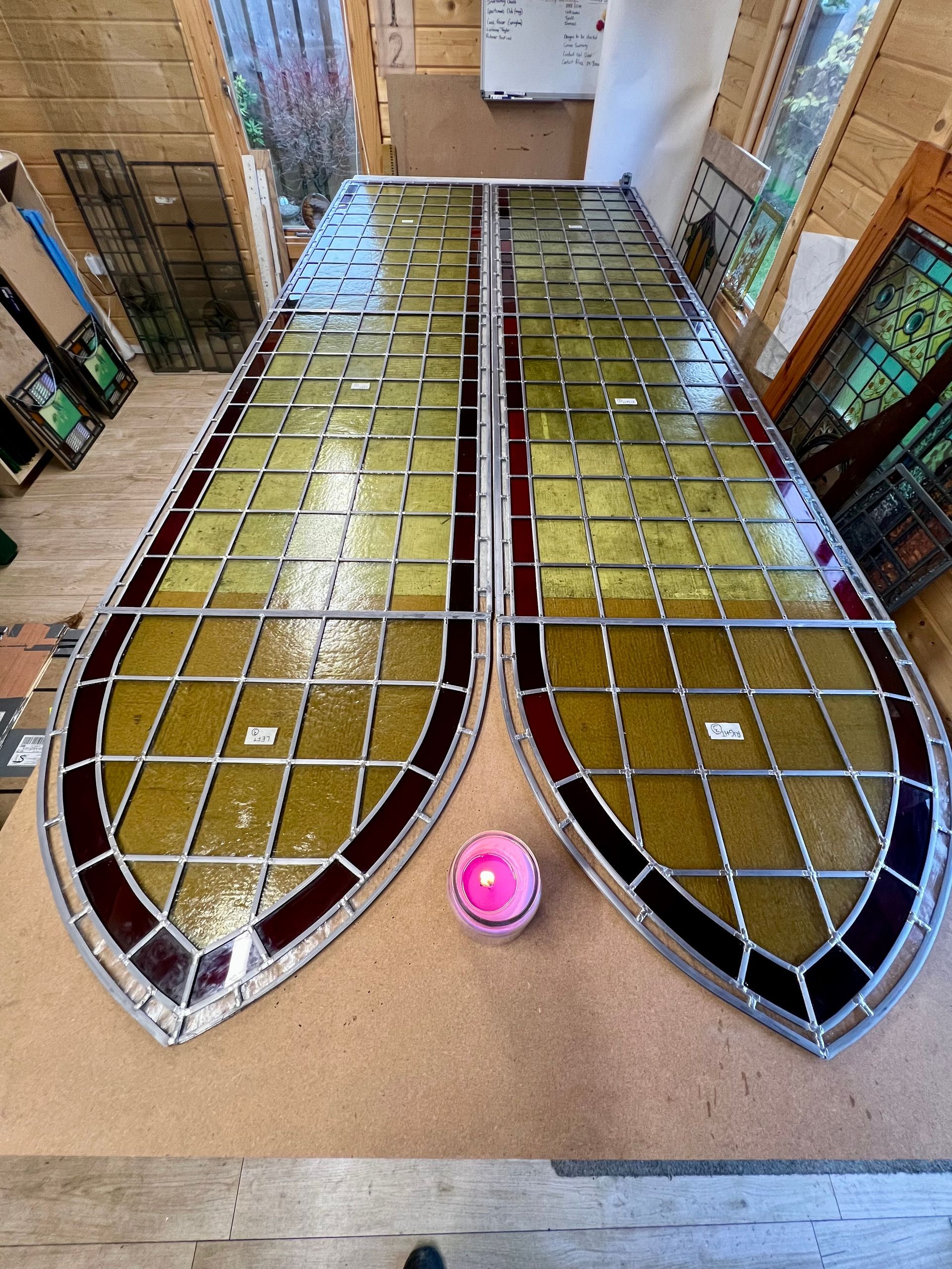 Two metal wing-like frames with yellow panels laid on a workshop floor, with a pink ball at the bottom center