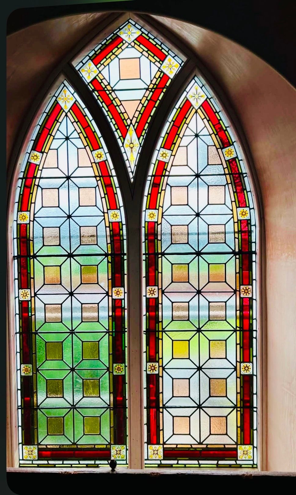 Colorful stained-glass window with two pointed arches and geometric patterns