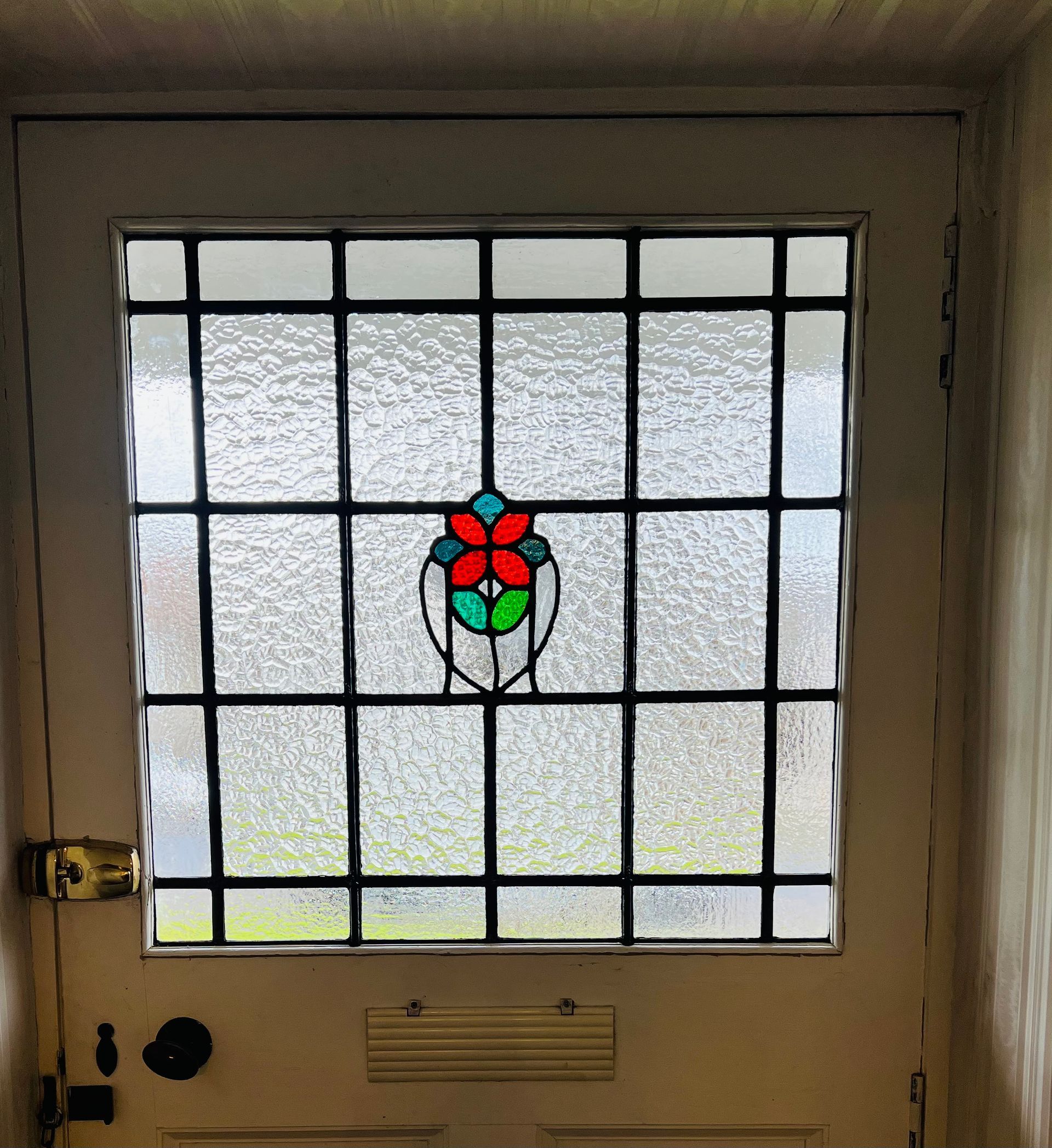Front door with frosted glass panes and a small red-and-green flower stained-glass panel.