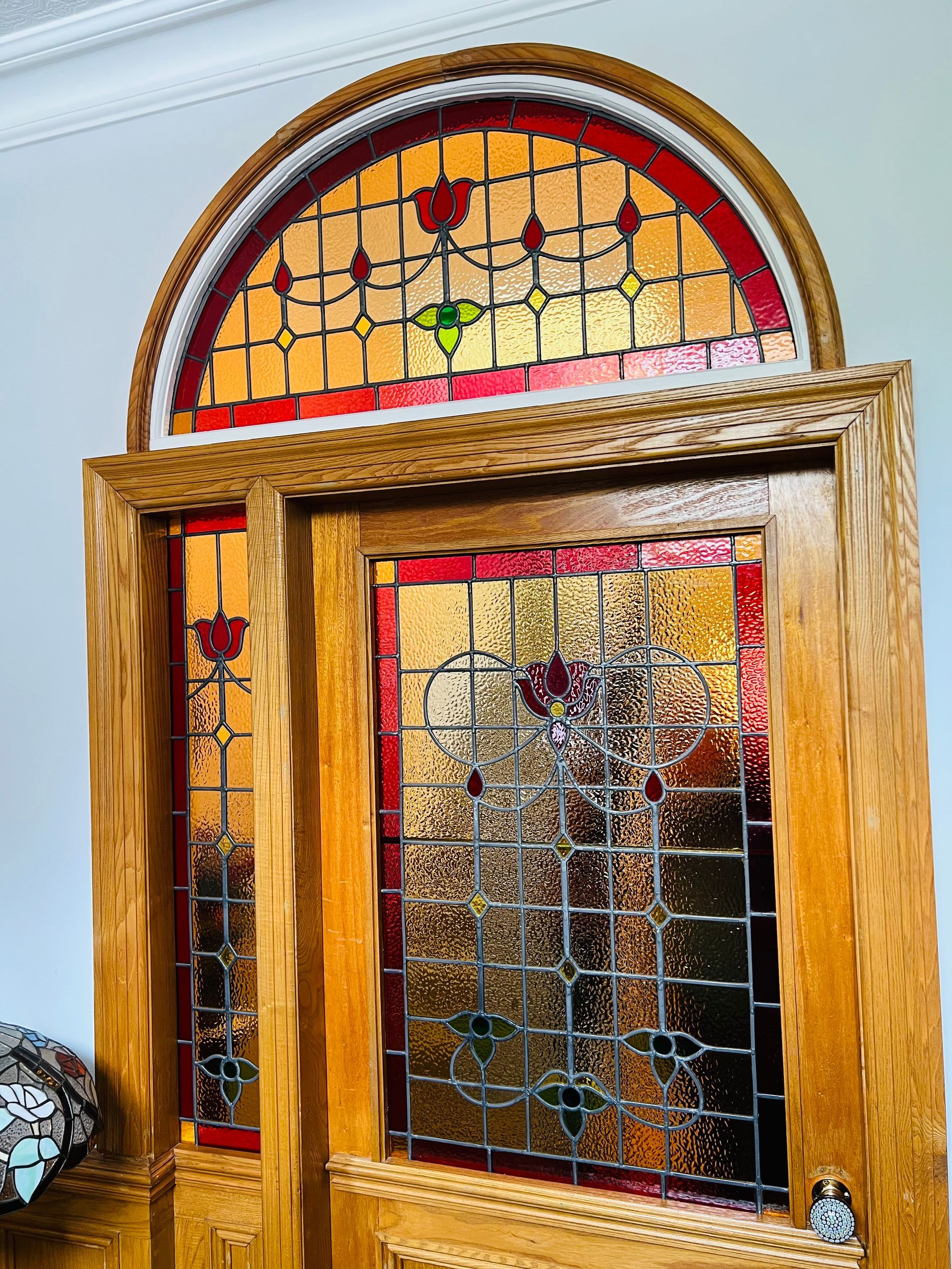 Wooden arched stained-glass window with a hinged pane and decorative floral design