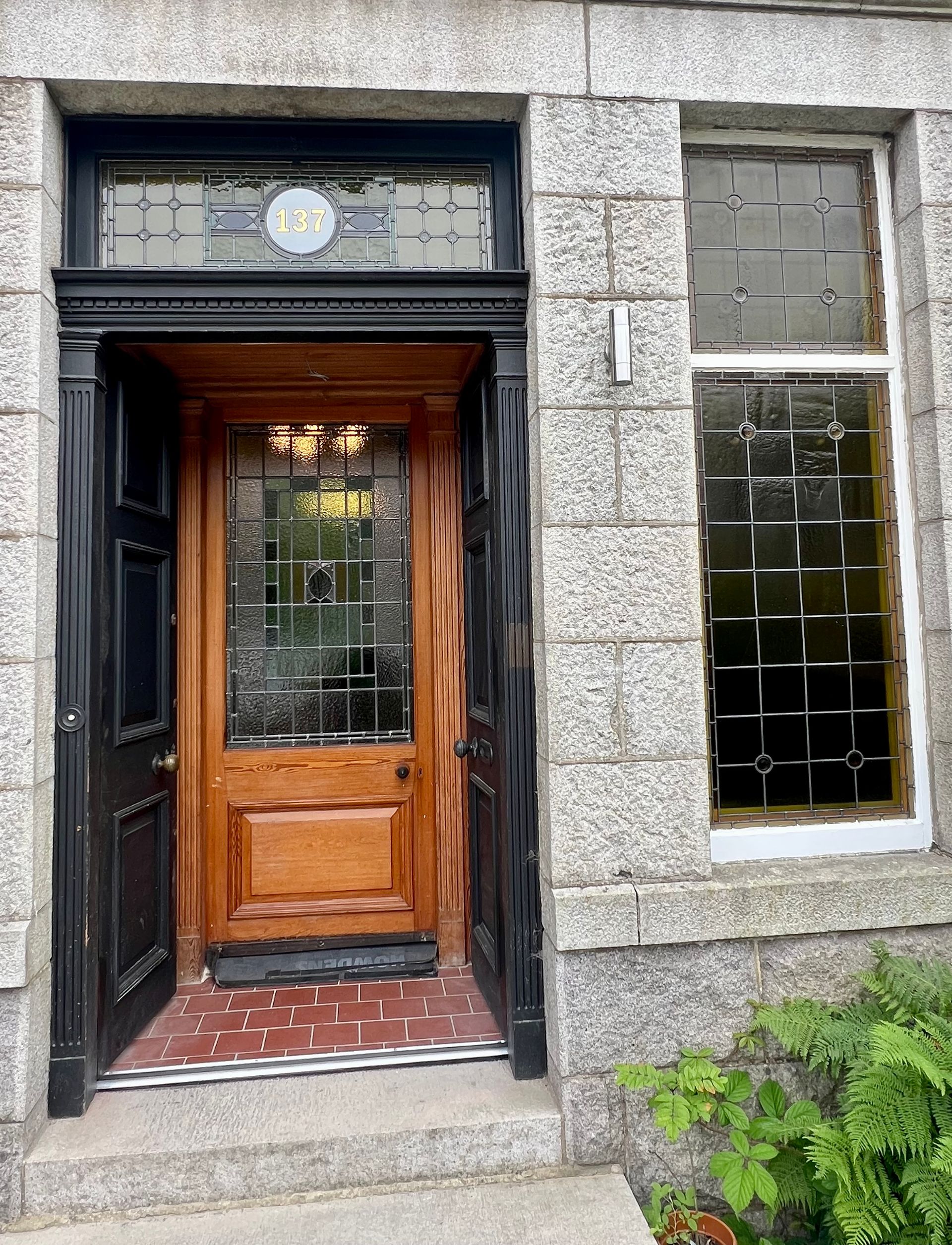 Stone building entrance with a wooden door and tall window beside it