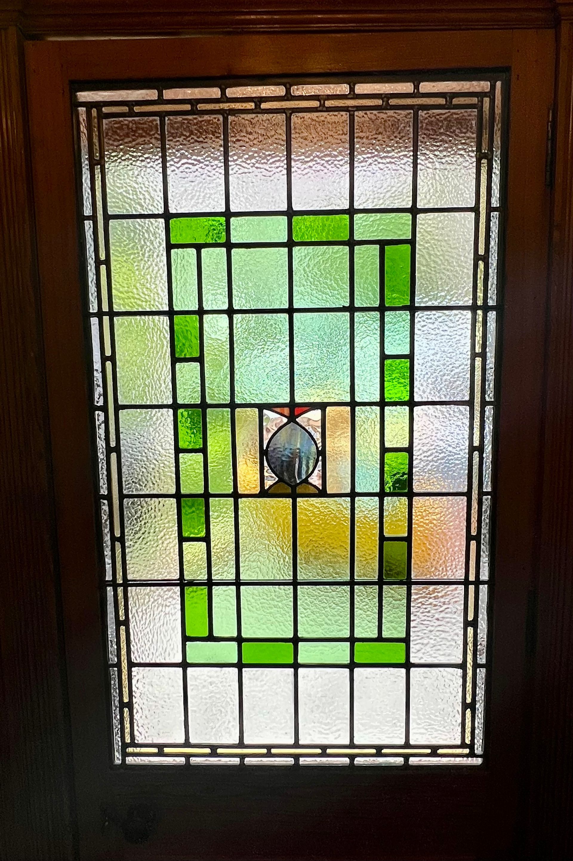 Stained-glass window with green border and a small bird in the center